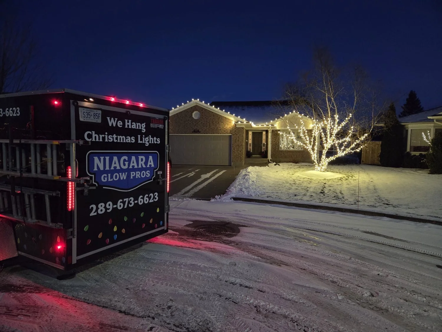 Snowy residential roofline and tree wrap with the Niagara Glow Pros trailer in Niagara Falls.