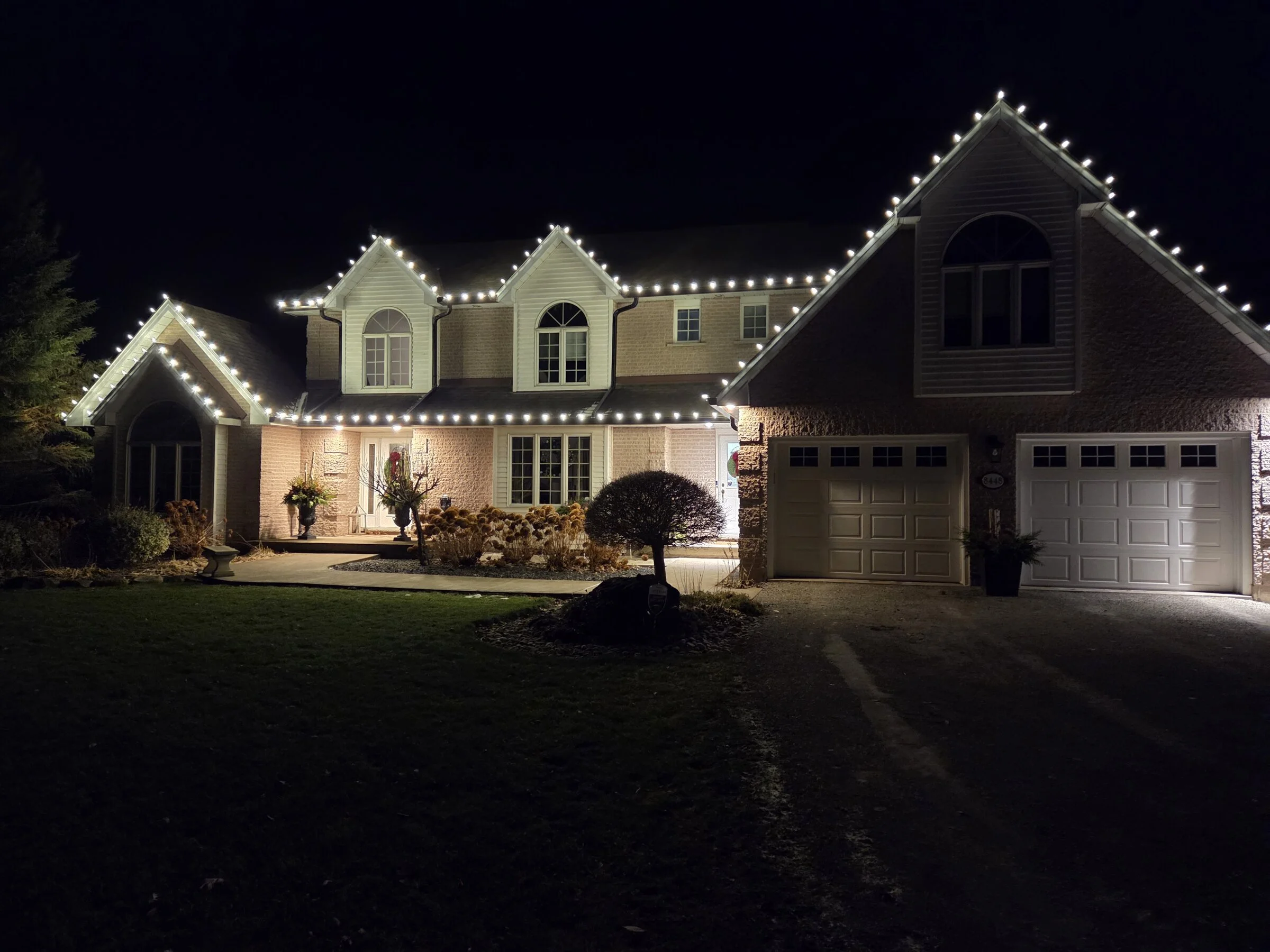 Large two-story home with complete warm-white roofline Christmas light package across every gable in Grimsby.