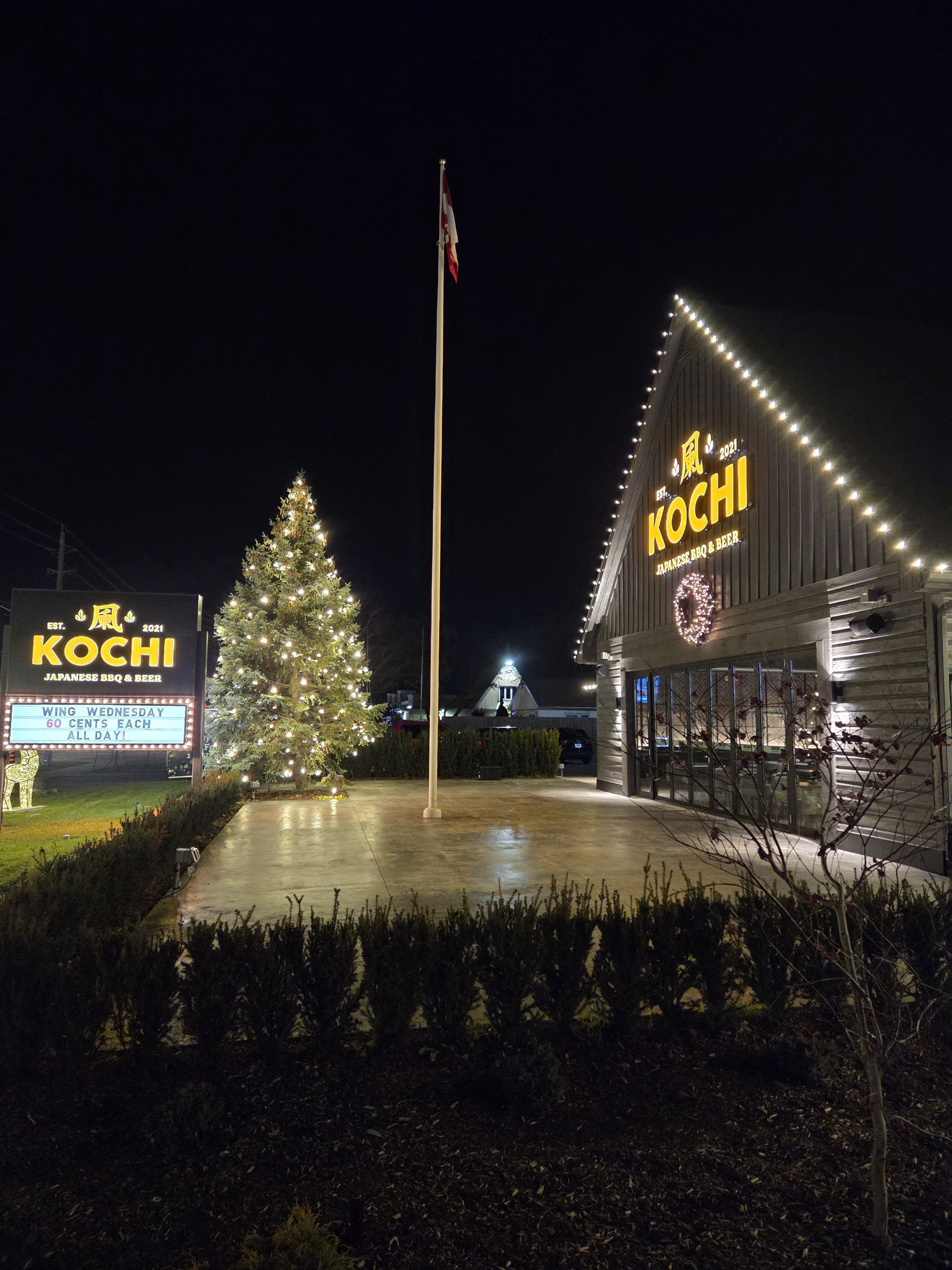 Warm-white tree wrap and roofline lights at Kochi Japanese BBQ with Niagara Glow Pros trailer in the foreground.
