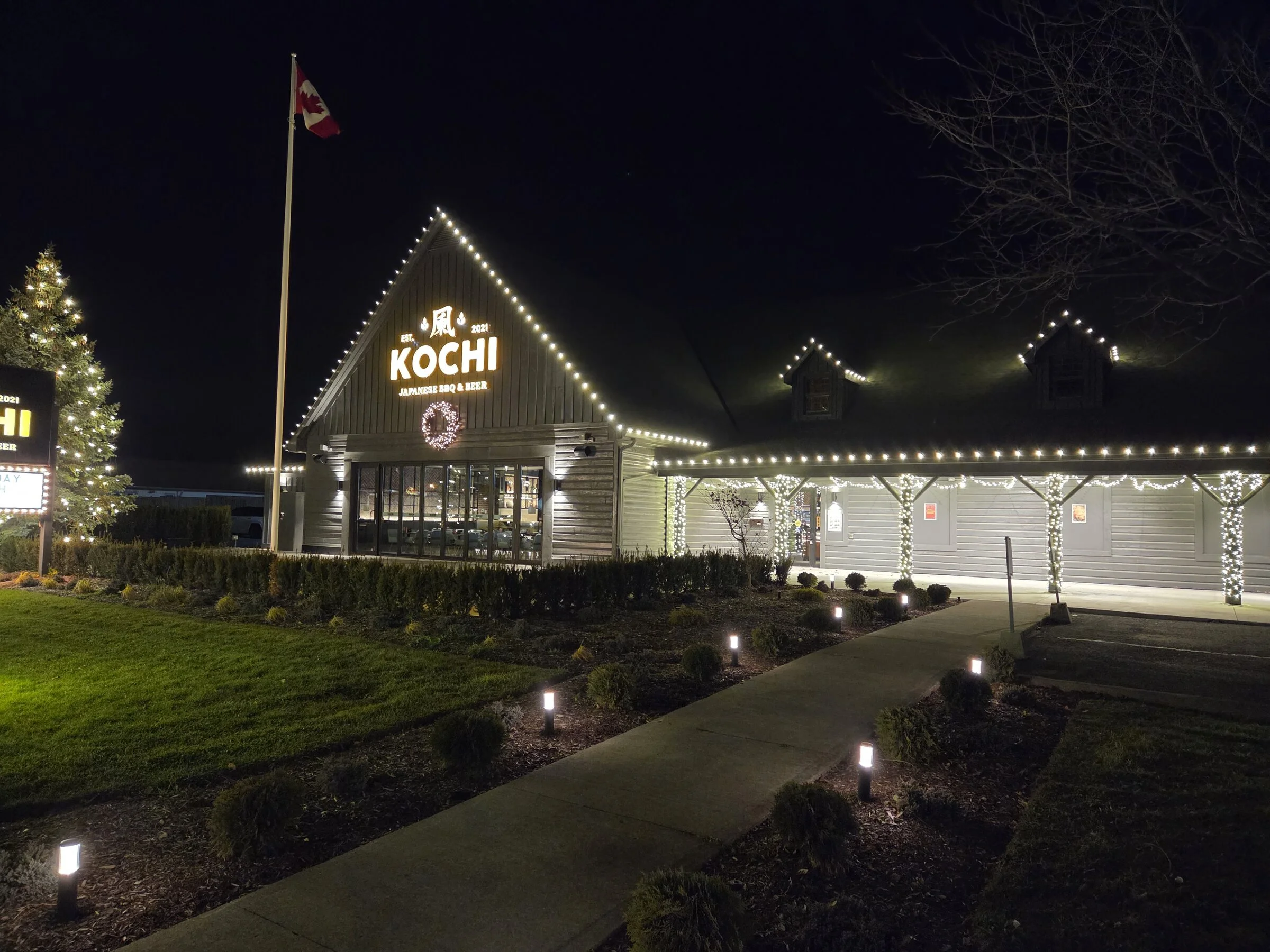 Complete Kochi storefront Christmas lighting with roofline, pillar wraps, tree wrap, and walkway lights in Niagara Falls.
