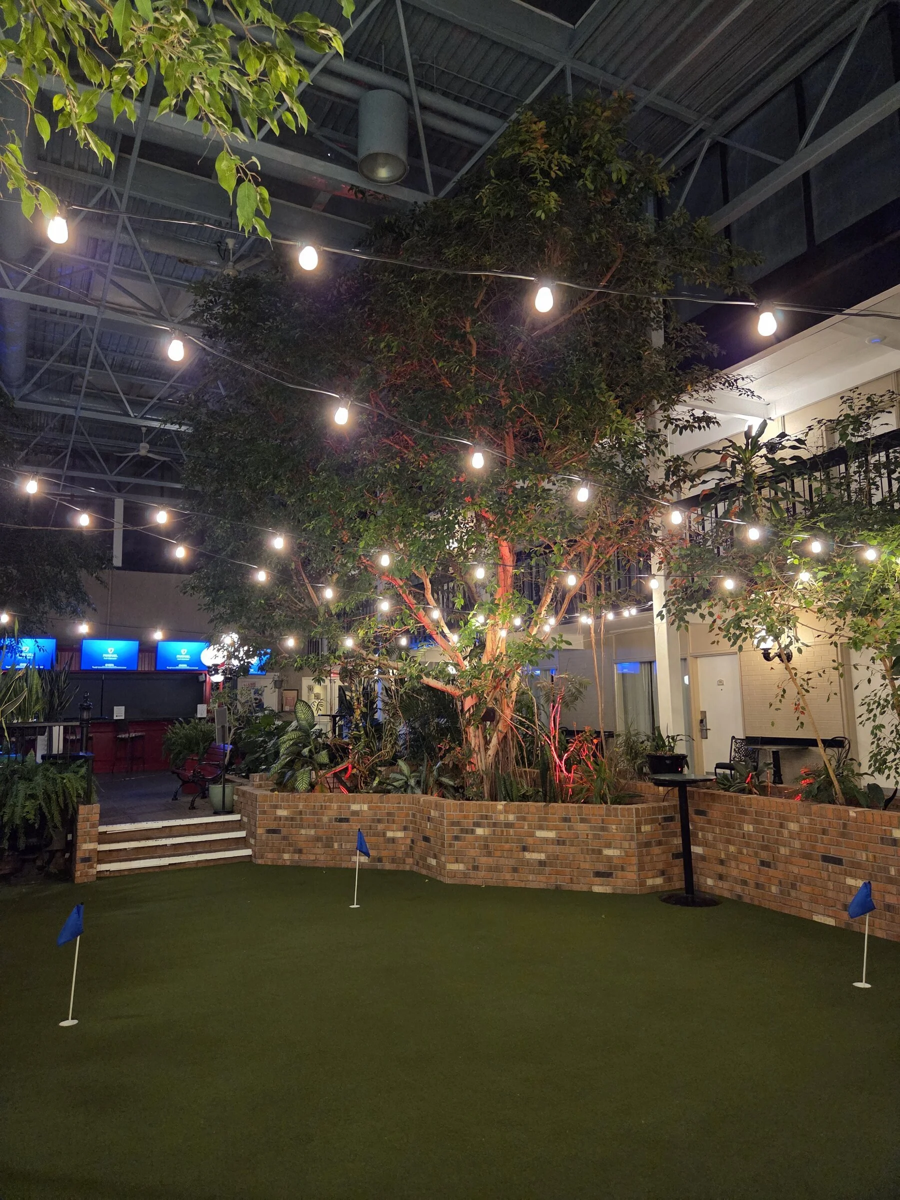 Indoor courtyard putting green looking toward hotel balconies under permanent bistro patio lights in Niagara Falls.
