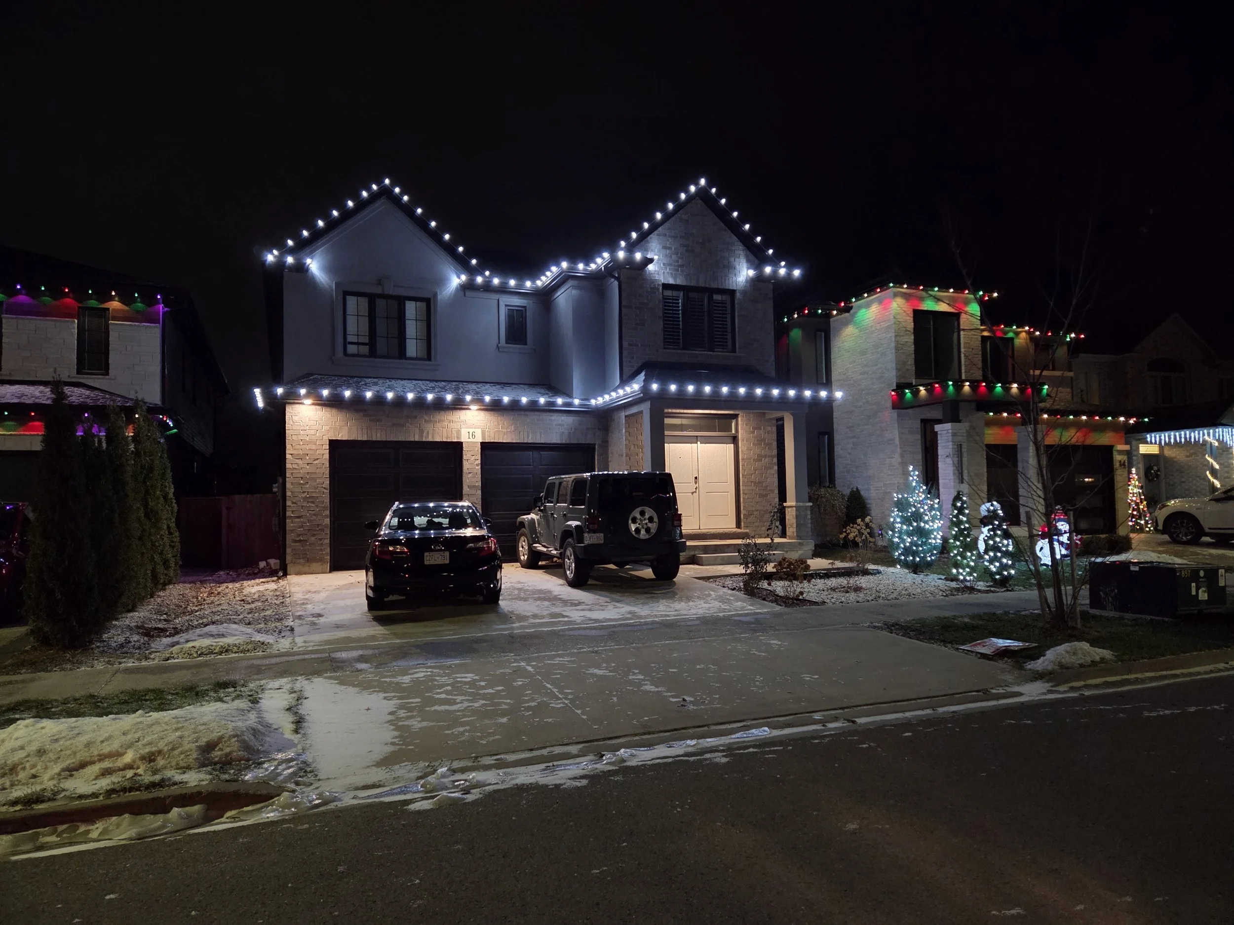 Christmas light installation in Fonthill (Pelham) with red and white roofline lights and warm-white bush wraps on a snowy evening — Niagara Glow Pros.