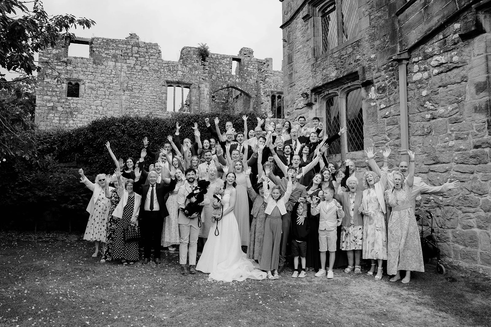 Large group picture at a wedding with bride and groom holding their two dogs 