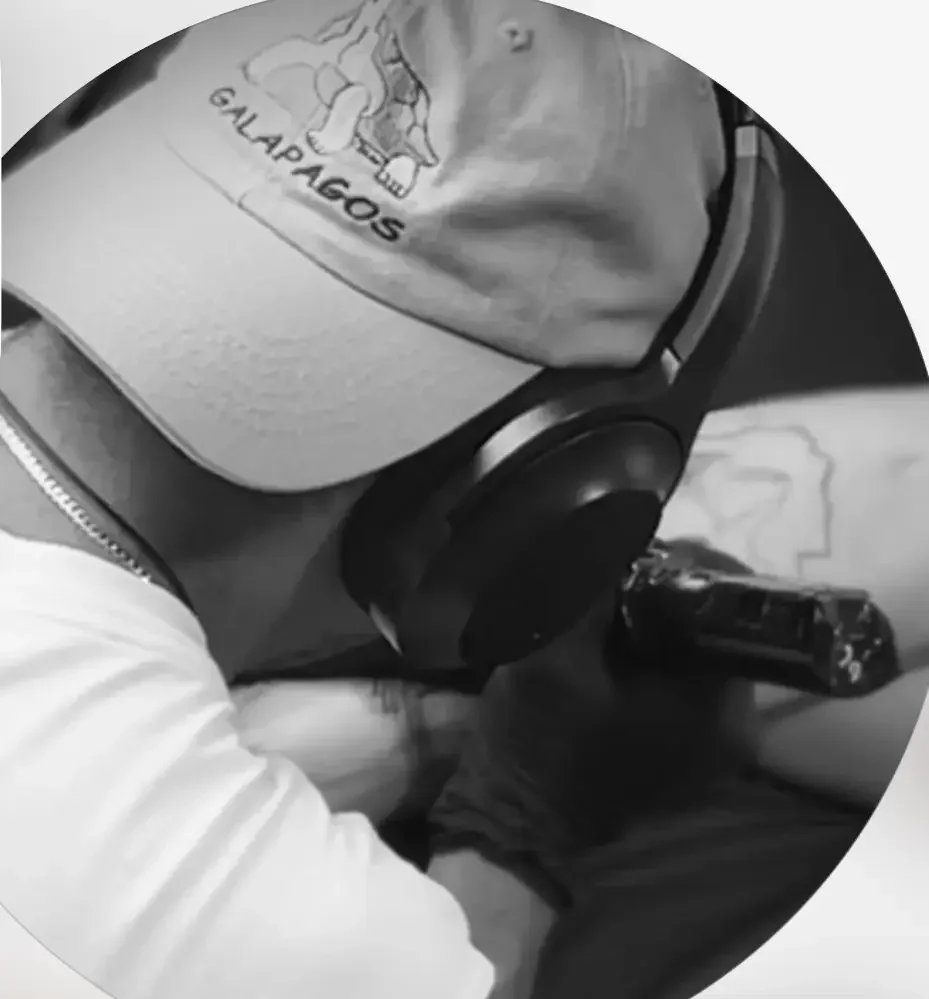 Une personne portant un casque anti-bruit et un T-shirt avec un tatouage qui indique 'GALAPAGOS' joue avec une arme à feu.