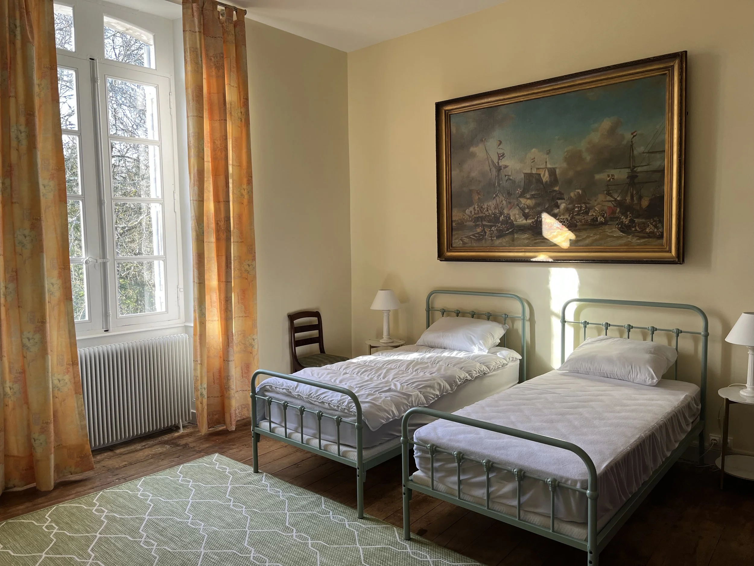 Une pièce avec deux lits, une grande armoire en bois et une chaise en bois contre un mur peint en jaune.