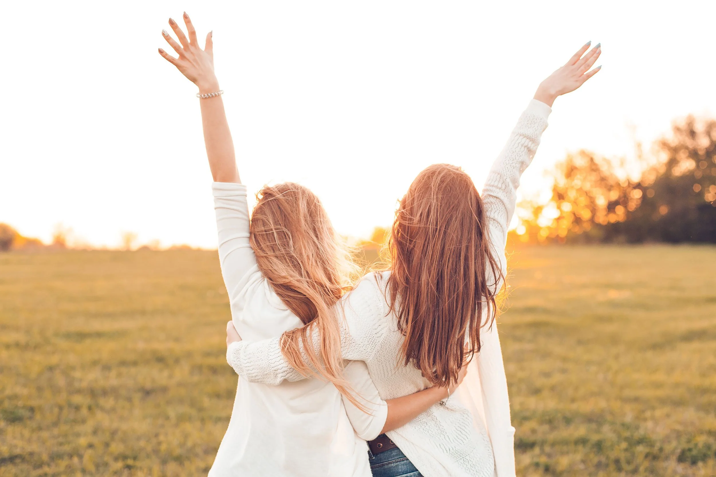 Two mothers with arms raised in celebration, representing the support found in Motherwell's Postpartum Circle in Austin and Cedar Park, TX