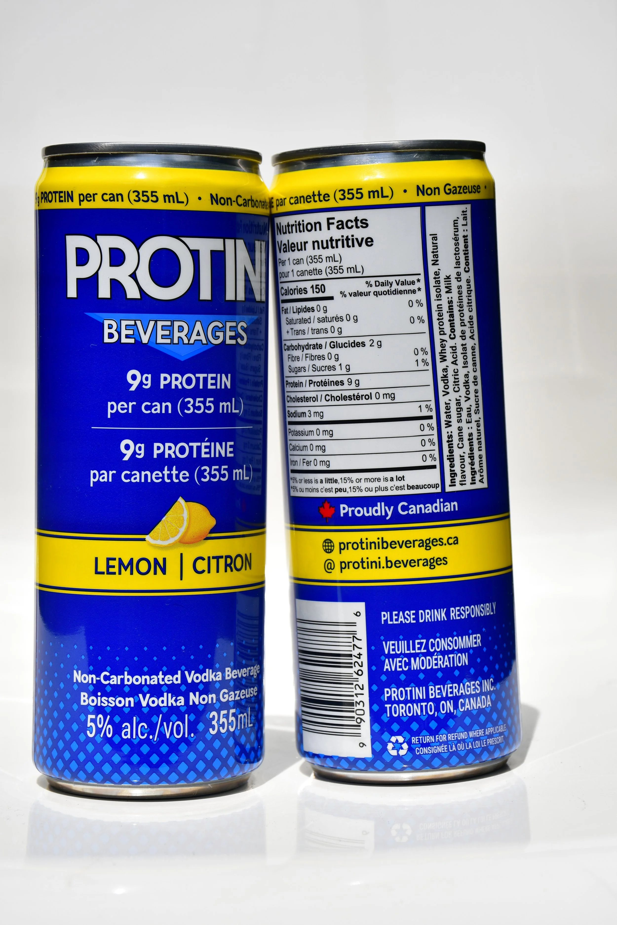 Two hands holding cans of Protini lemon-flavored vodka beverages up towards a clear blue sky.