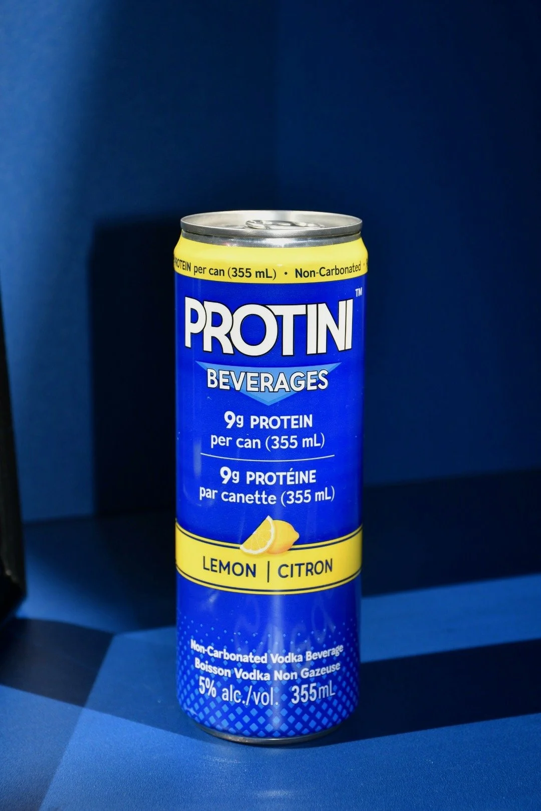 Cans of Protini lemon-flavored vodka beverage lying on ice.