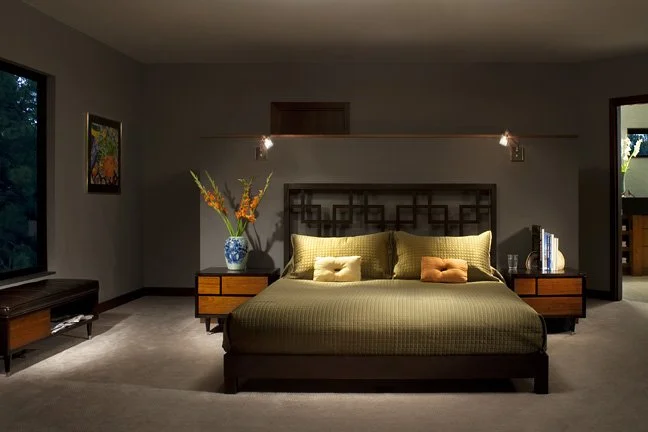 A bedroom with a bed, nightstands, and lamps, with a window showing trees outside. Custom Home built in Montana by Edgell Building.