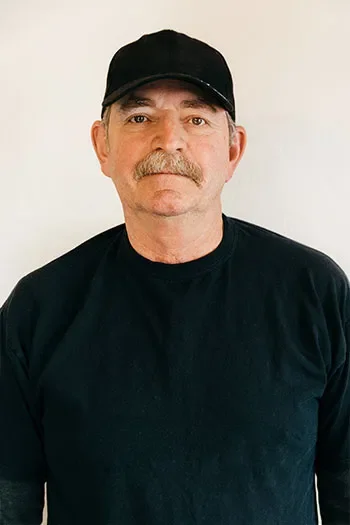 Chip Dominicak of Edgell Building. Man with a mustache wearing a black cap and black shirt standing against a plain white background.