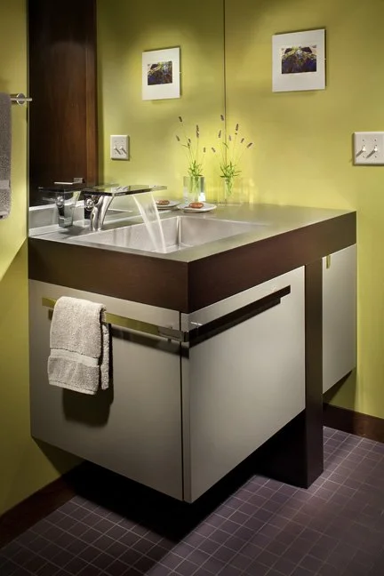 Bathroom sink with countertop, mirror, towels, and framed pictures on a lime green wall. Custom Home built in Montana by Edgell Building.