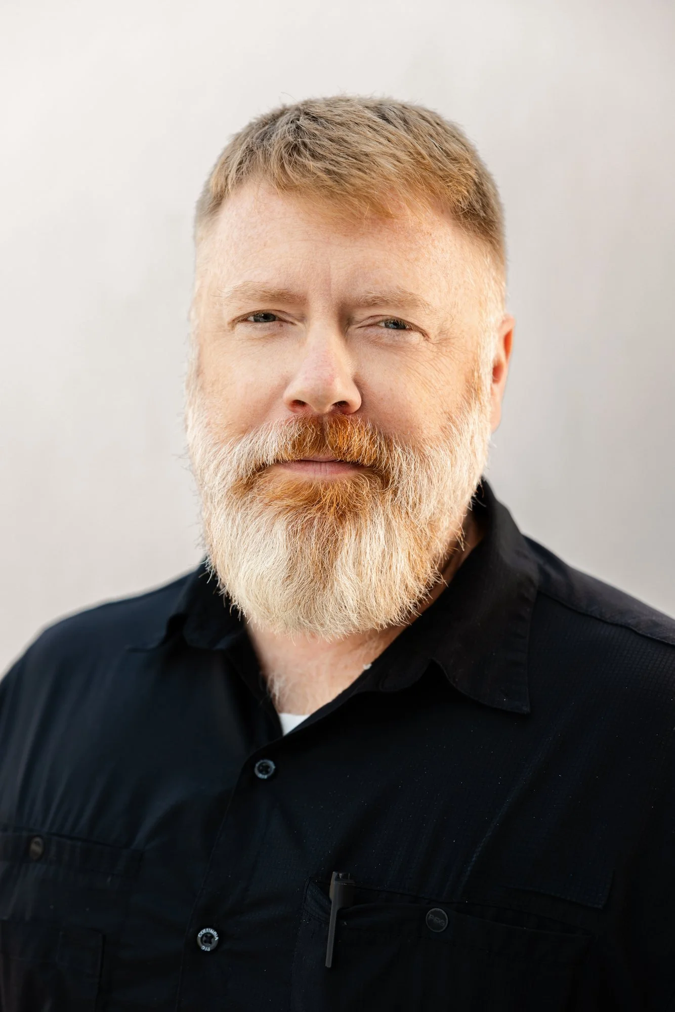 Mason Goeman of Edgell Building. A man with short reddish-brown hair and a full beard, wearing a black button-up shirt against a plain light background.