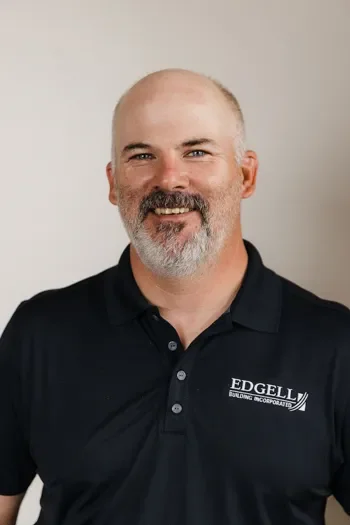 Ted Dunton of Edgell Building. Man with a beard and mustache wearing a black polo shirt with the Edgell Building Incorporated logo, smiling against a plain background.