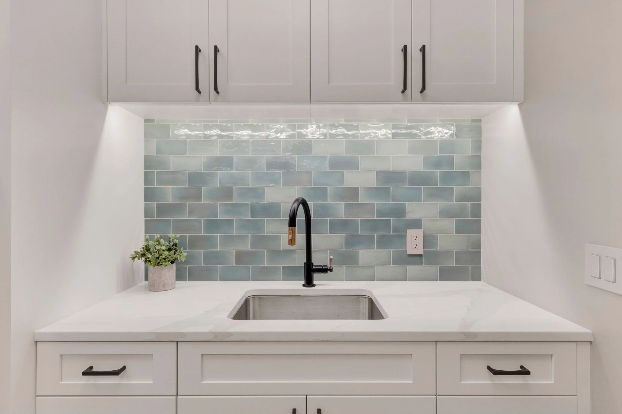 Kitchen sink with dark faucet, white cabinetry, and a light gray tiled backsplash. Custom Home built in Montana by Edgell Building.