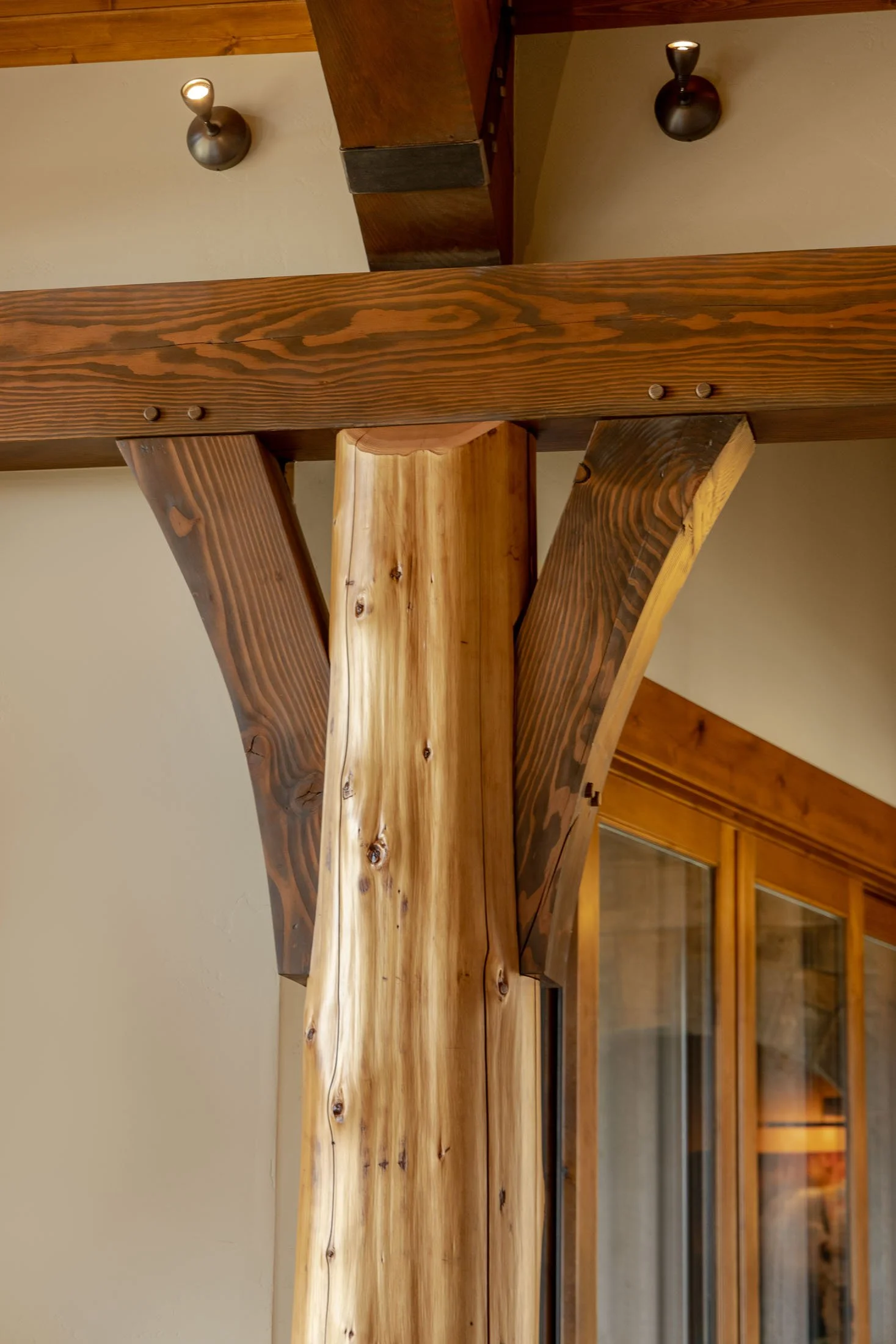 Close-up of a wooden room divider with a vertical support beam and two vertical side beams with a wood grain pattern. Custom Home built in Montana by Edgell Building.