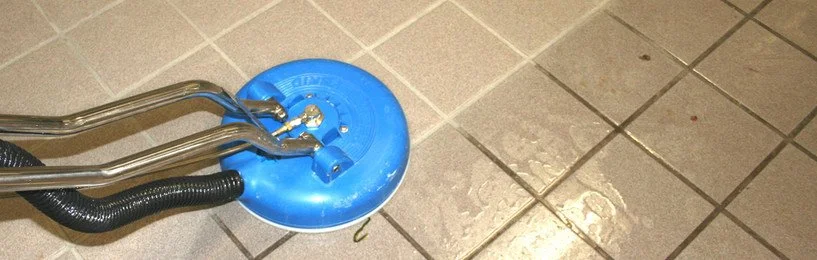 A grout removal tool with a blue disc attached to a tiled floor