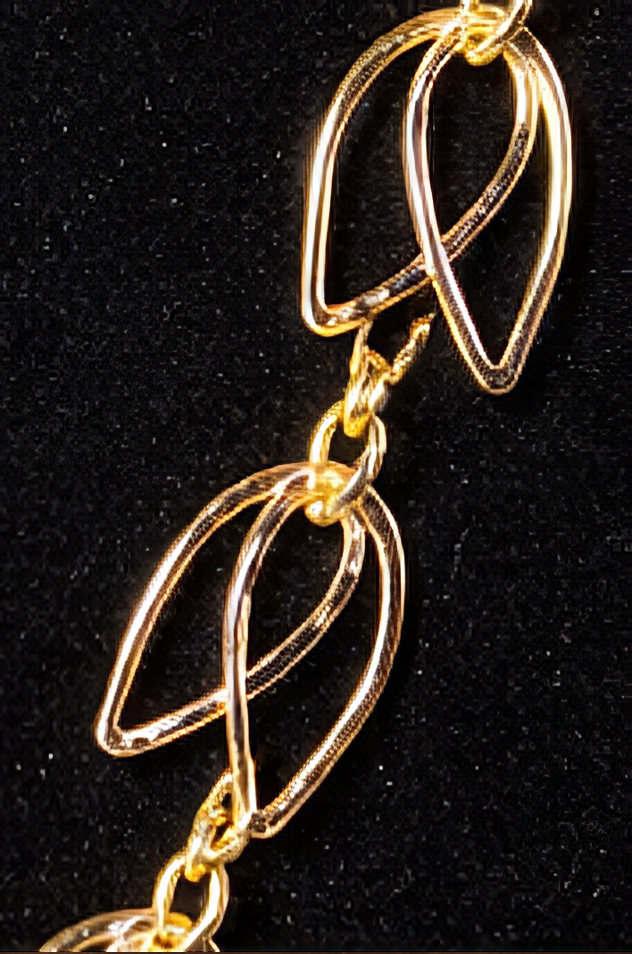 Close-up of gold intertwined leaf-shaped jewelry pieces (from "gold chain necklace") on black background.