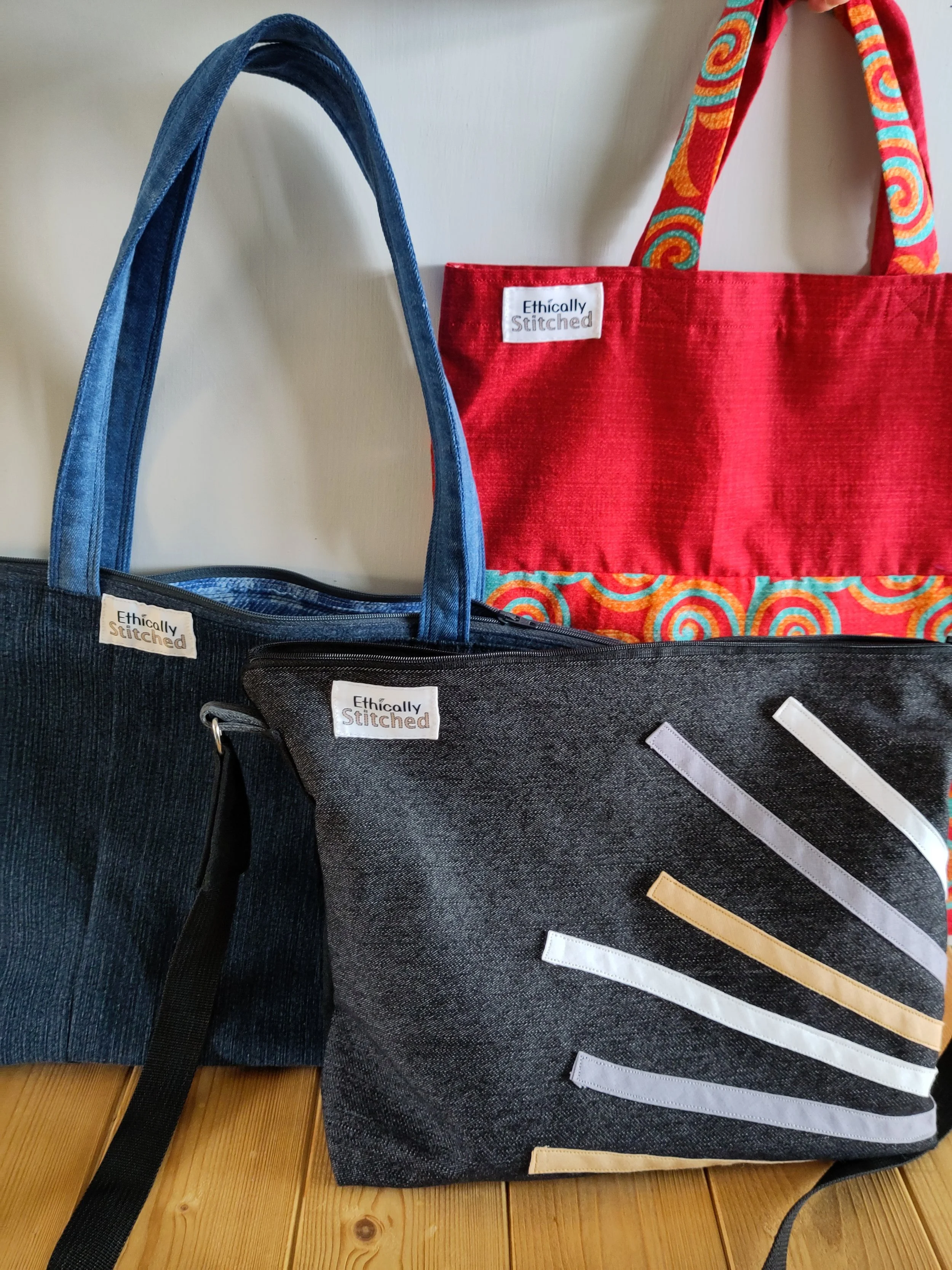 Black denim crossbody bag and blue denim tote bag and red patterned shopping bag