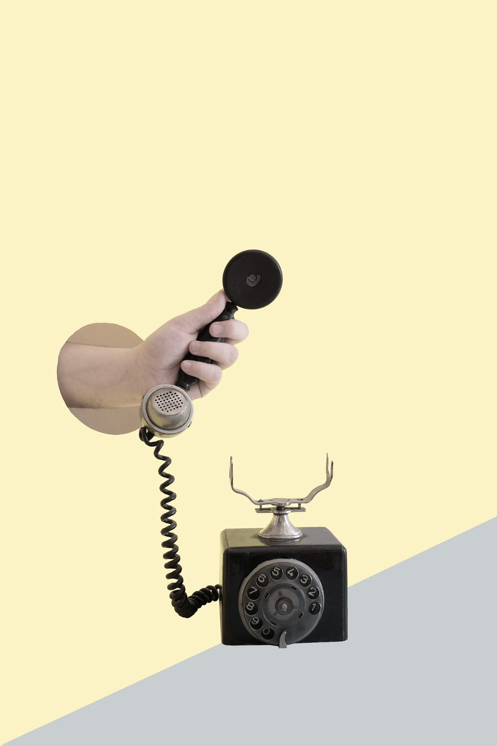 Teléfono antiguo con auricular en mano y base con disco giratorio, encima un soporte metálico en forma de horquilla para sostener el teléfono. Queixos Ángel