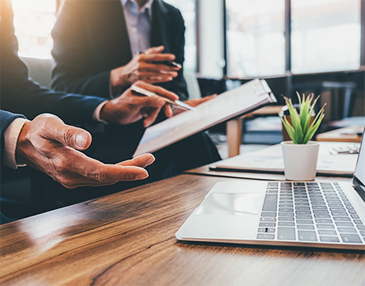 Business professionals collaborating around a laptop in a modern office representing OC Videography corporate and brand video production for businesses and entrepreneurs.