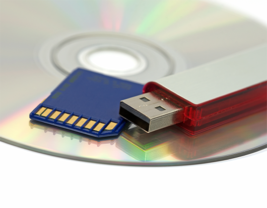 Close-up of a USB flash drive, SD memory card, and optical disc representing OC Videography’s media duplication services.