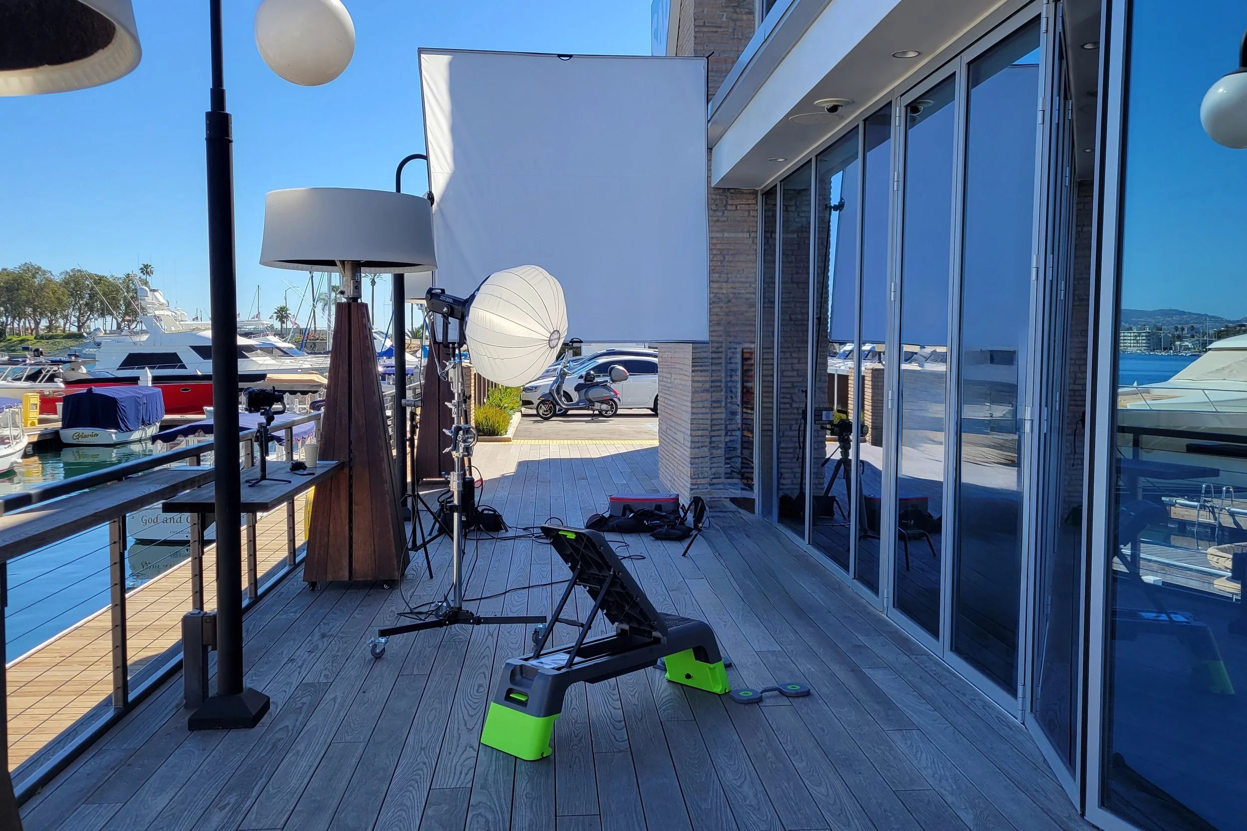 Outdoor video production setup at the Newport Beach harbor with tripods, cameras, and lighting, showcasing on-location filming for commercials and lifestyle content by OC Videography.