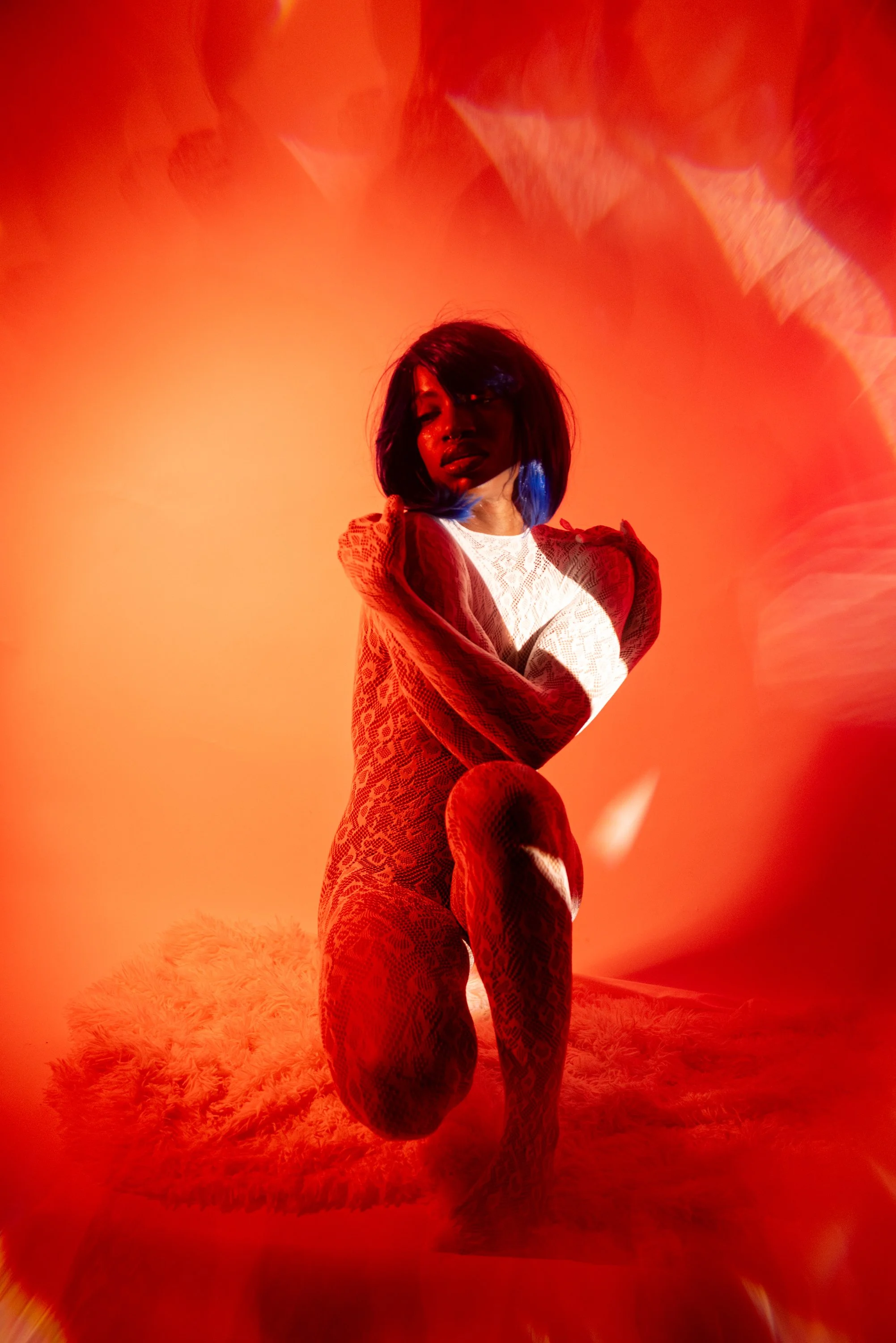 Red light boudoir  session with Djau, showcasing bold lighting and elegant pose.