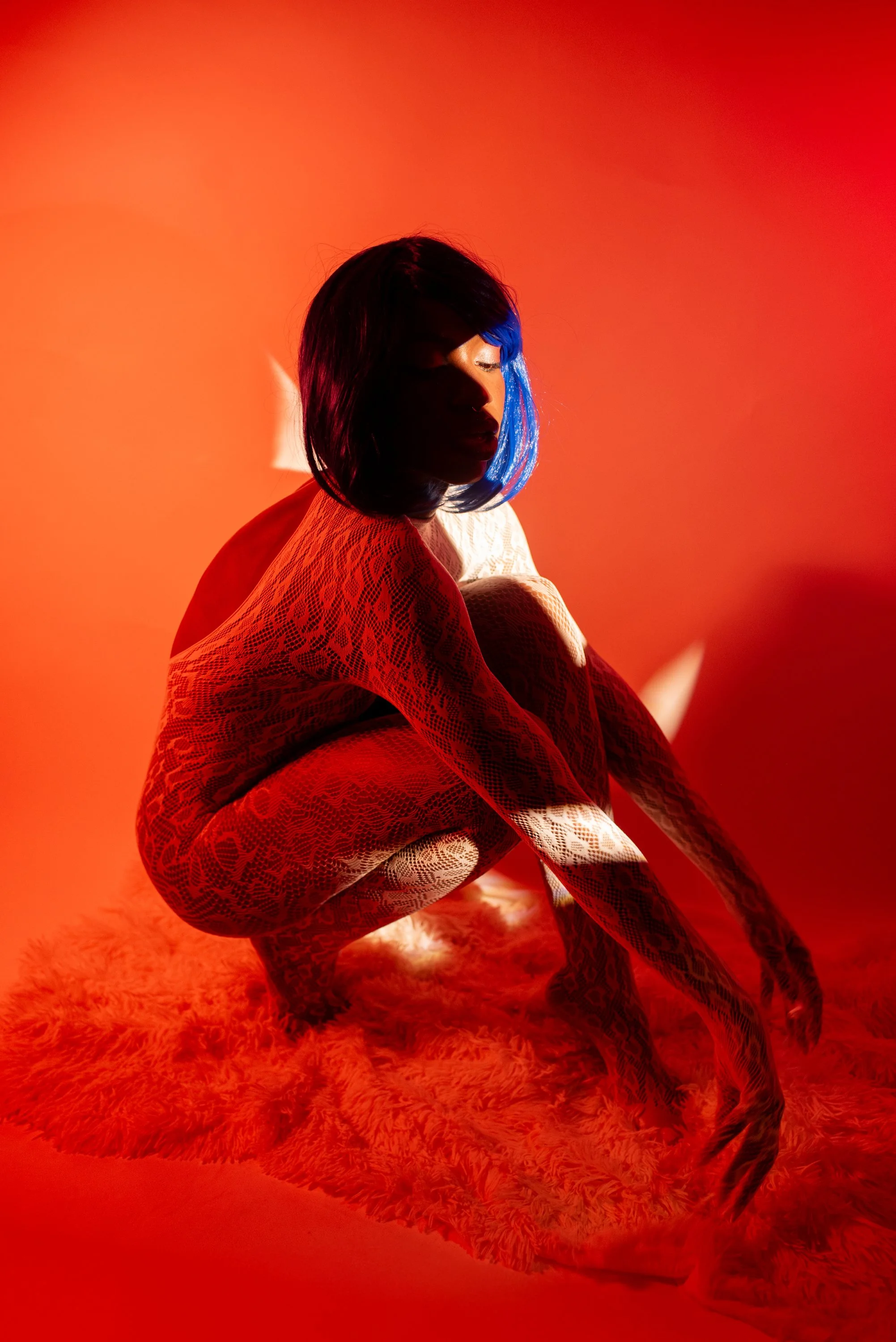 Red light boudoir  session with Djau, showcasing bold lighting and elegant pose.