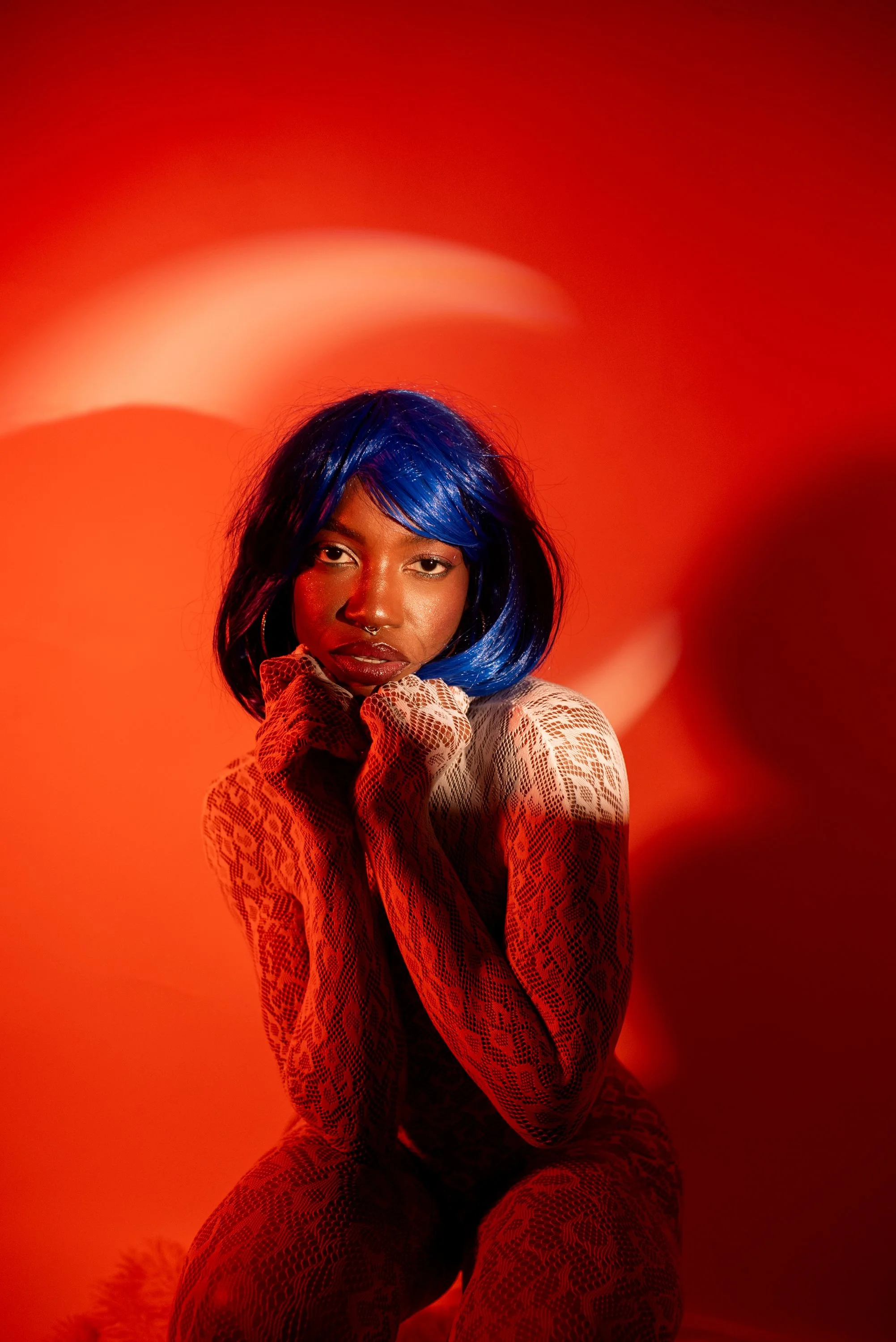 Red light boudoir  session with Djau, showcasing bold lighting and elegant pose.