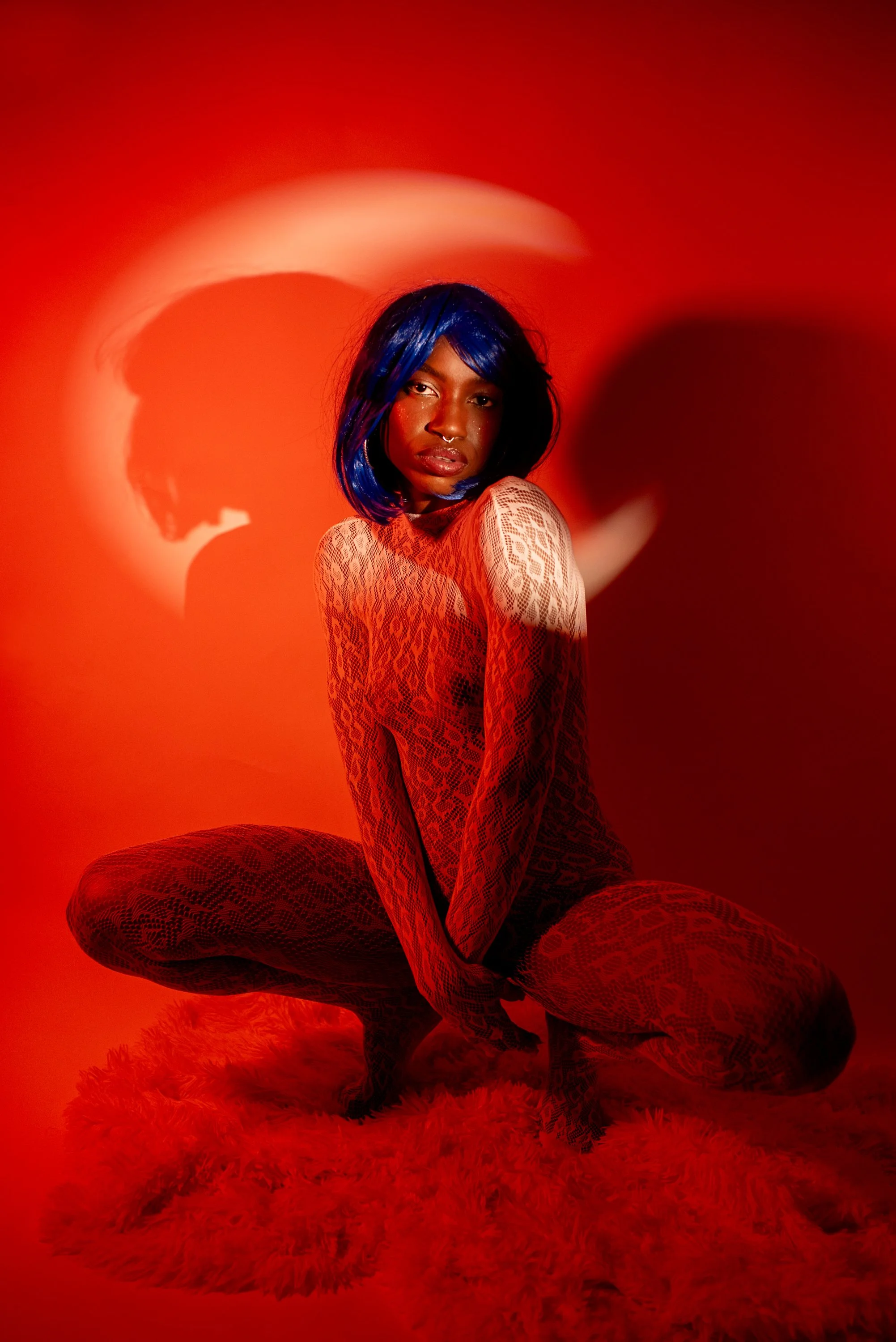 Red light boudoir  session with Djau, showcasing bold lighting and elegant pose.