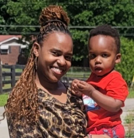 A woman holding a young boy outside on a sunny day.