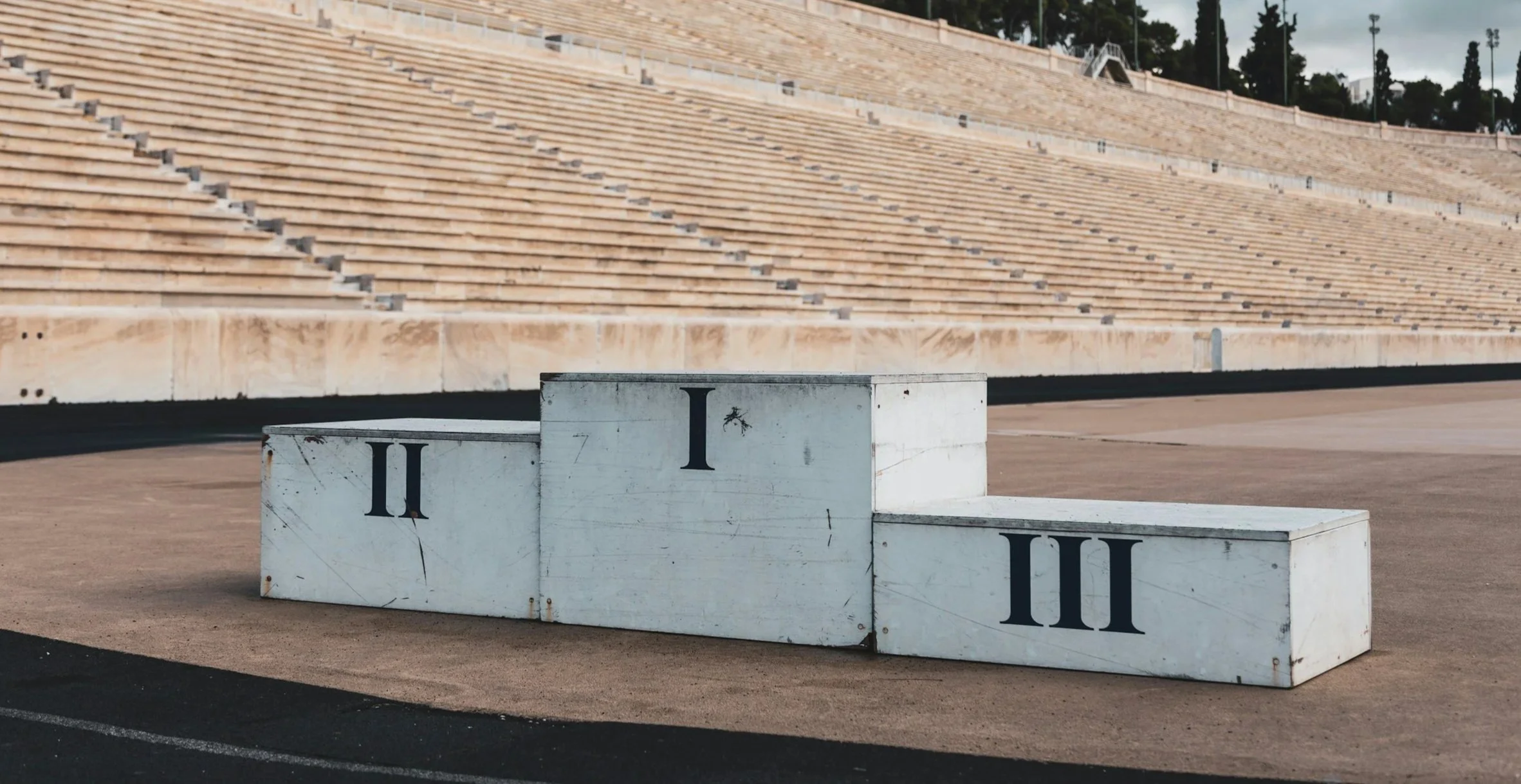 Award podium with three levels labeled I, II, and III in front of empty stadium seats.