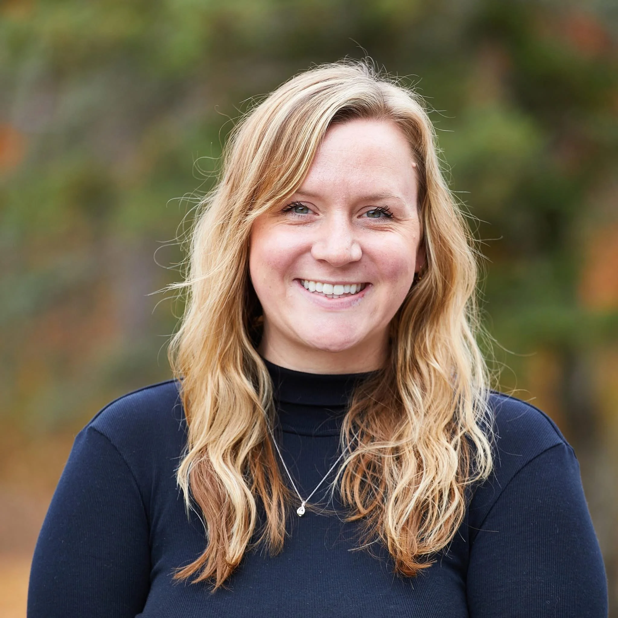 Two hands reaching toward each other near the center of the image, with a background of tall, gray concrete walls that form a narrow passageway, appearing to be a modern architectural structure.