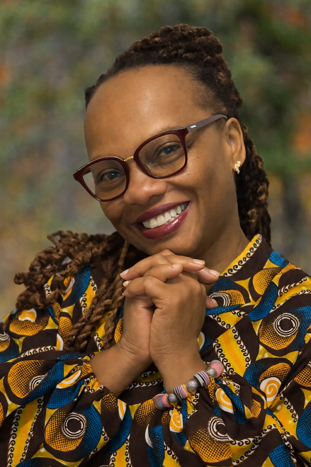 A family of three holding hands and standing in the shallow water at the beach on a sunny day, with waves approaching and a partly cloudy sky.