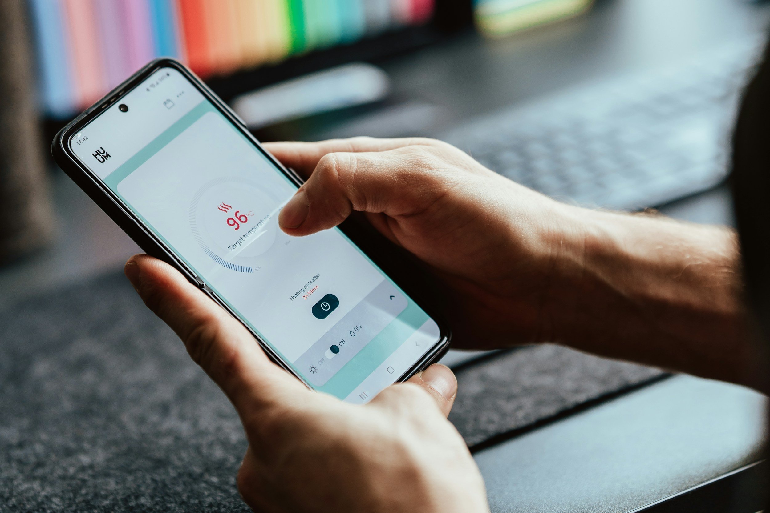 Person holding a smartphone with a temperature control app open, showing a target temperature of 96°C.