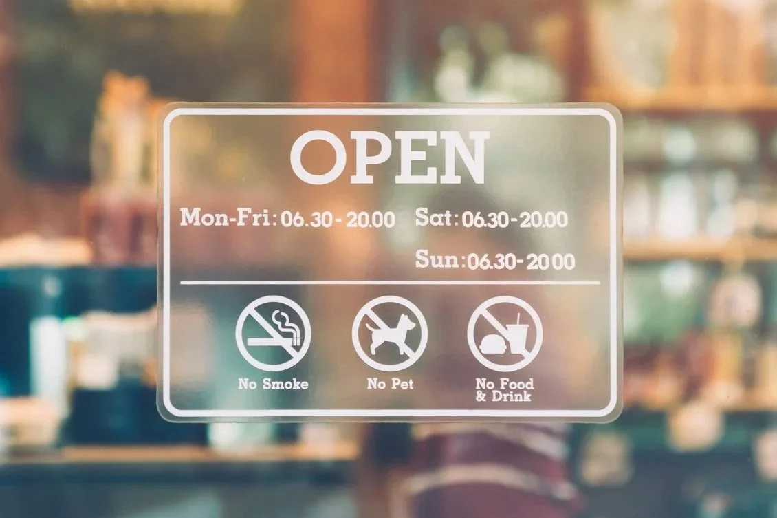 Glass door sign with hours, 'Open,' and icons indicating no smoking, no pets, and no food or drinks inside.
