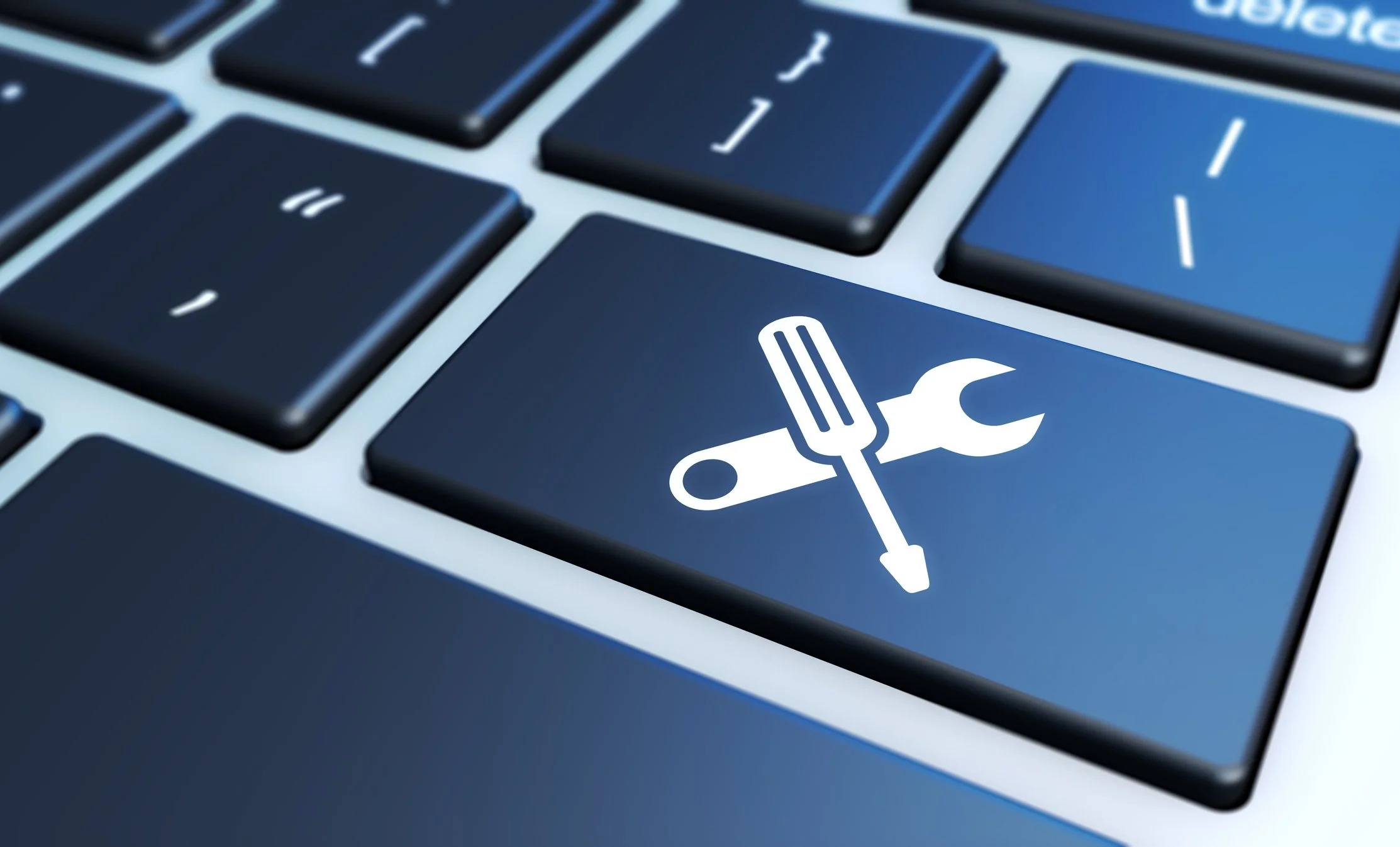 Close-up of a blue computer keyboard with a key featuring a white repair and tools icon, including a wrench, screwdriver, and paintbrush.