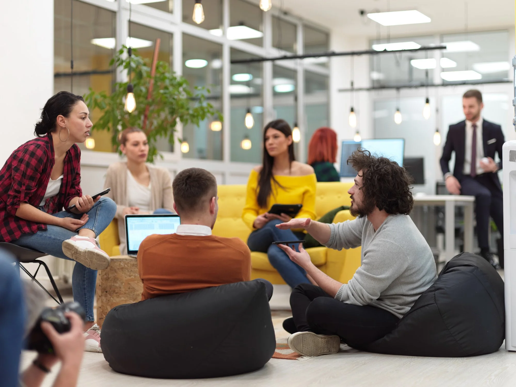 Group of young adults having a discussion in a modern office lounge.