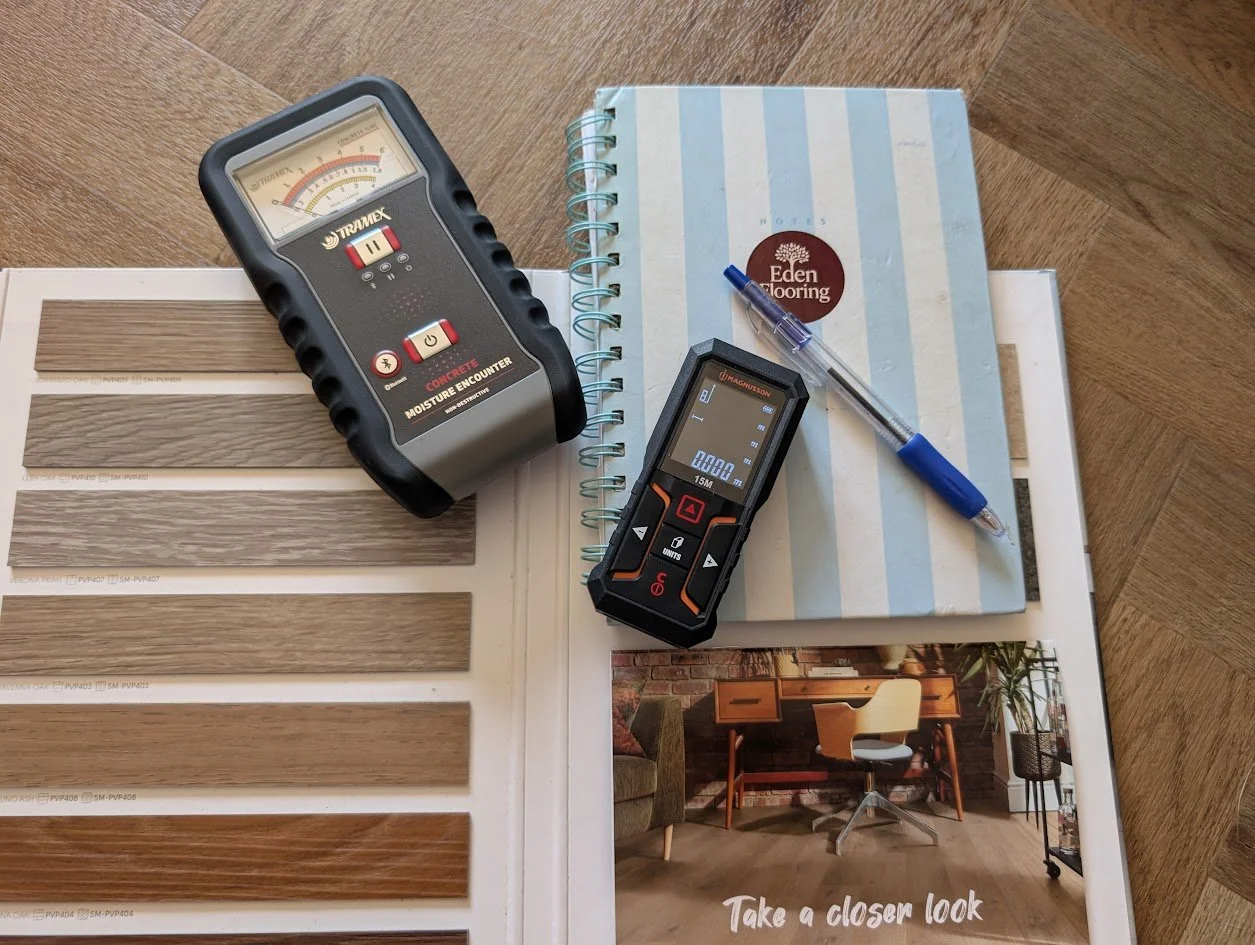 A notebook, a red pen, and a tape measure on a wooden surface.