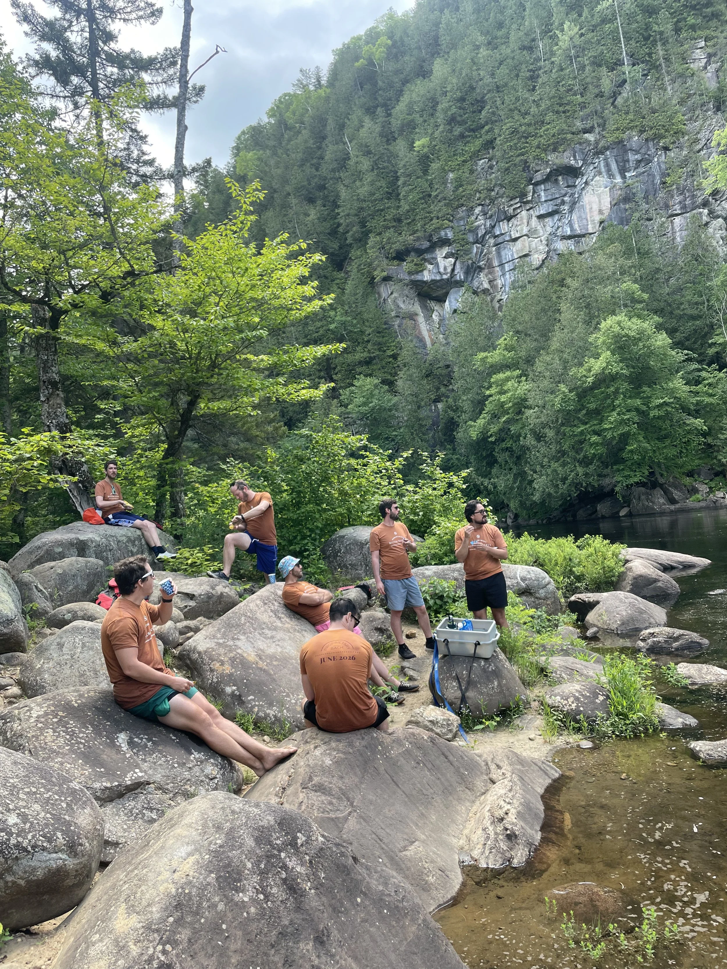 Whitewater rafting guests enjoying a riverside lunch along the Hudson River during an Adirondack rafting trip.