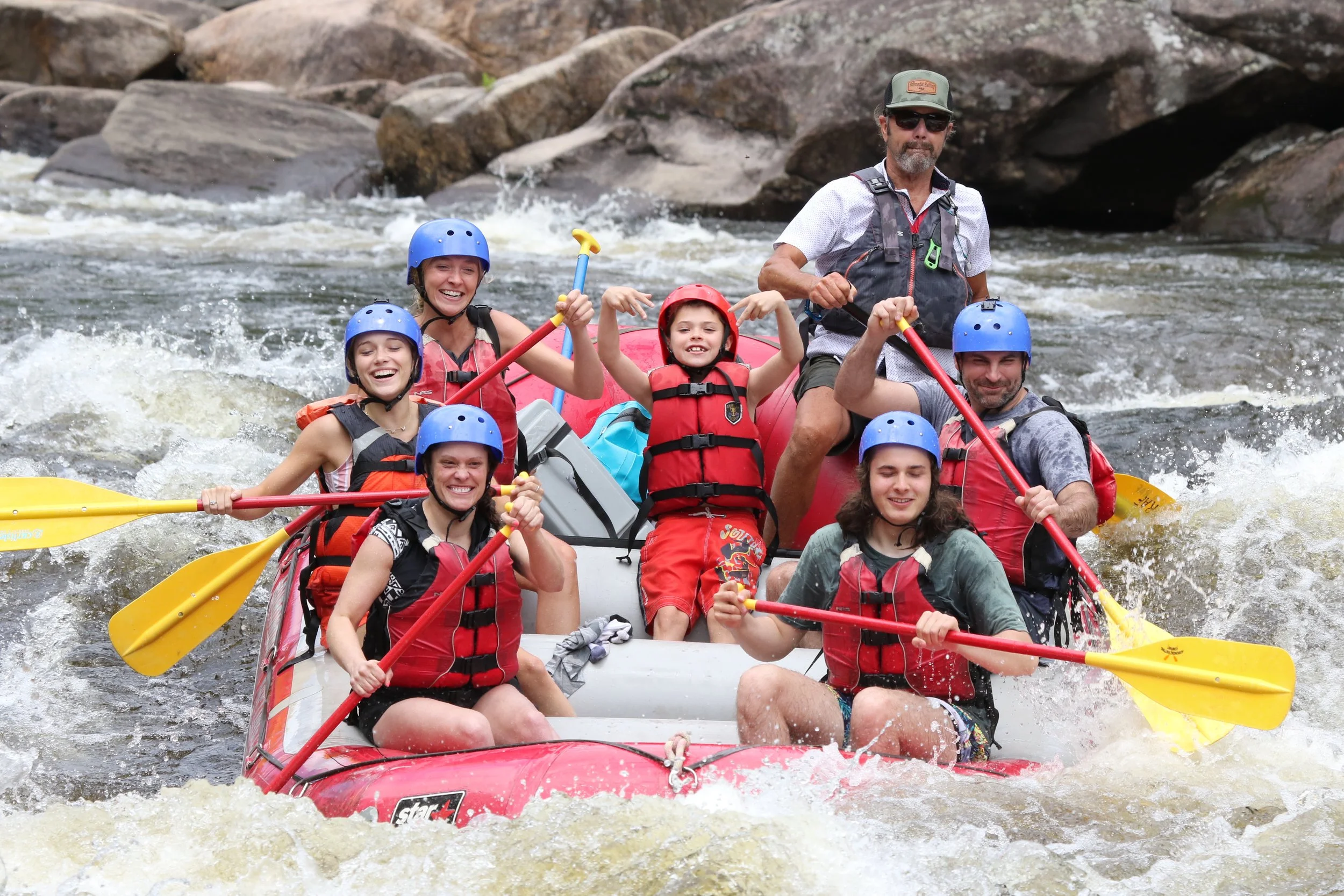 Family enjoying a guided whitewater rafting trip together on the Hudson River in the Adirondack Mountains.
