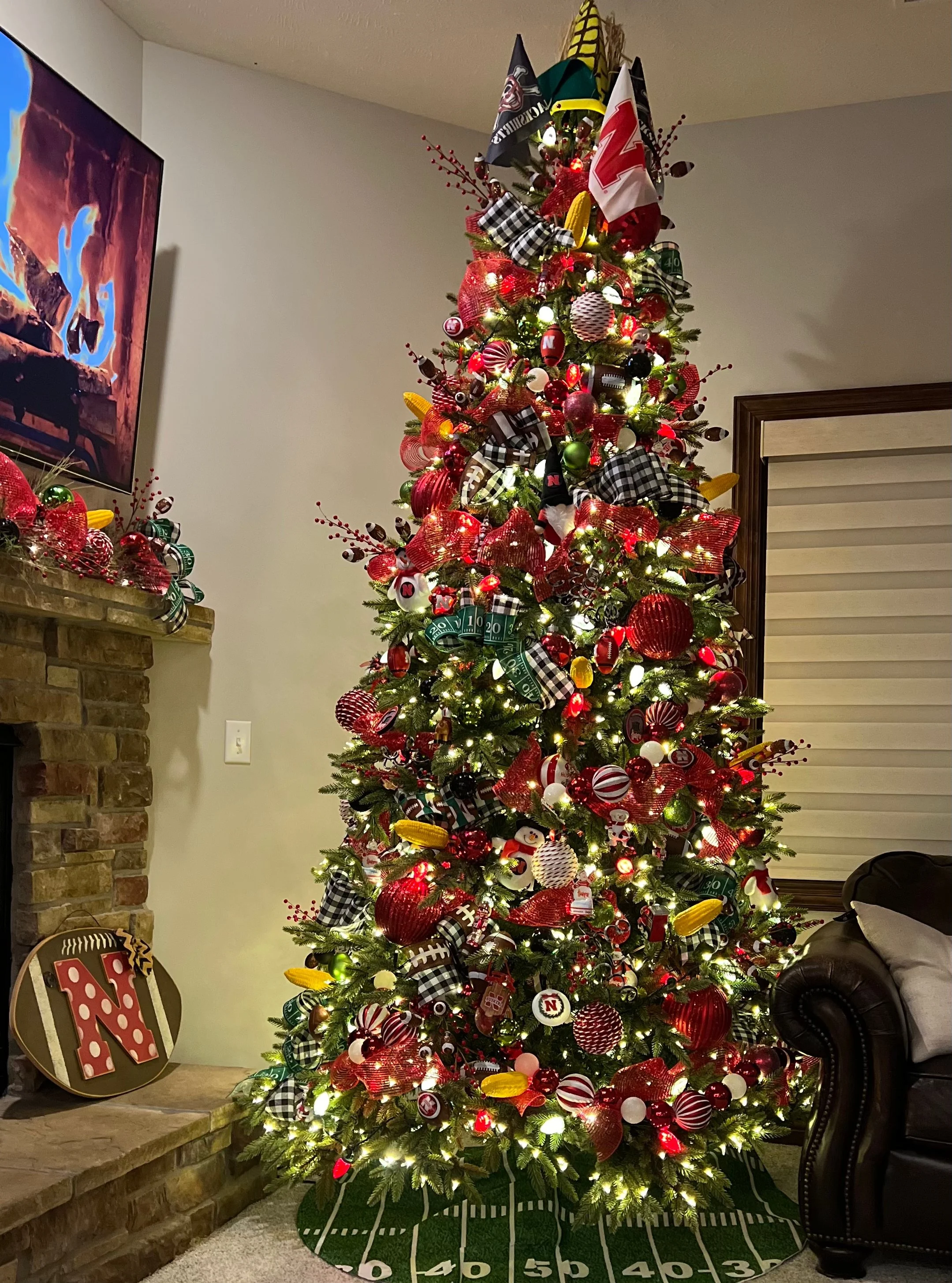 Decorated Christmas tree with red, black, white, and yellow ornaments and ribbons in a living room setting.