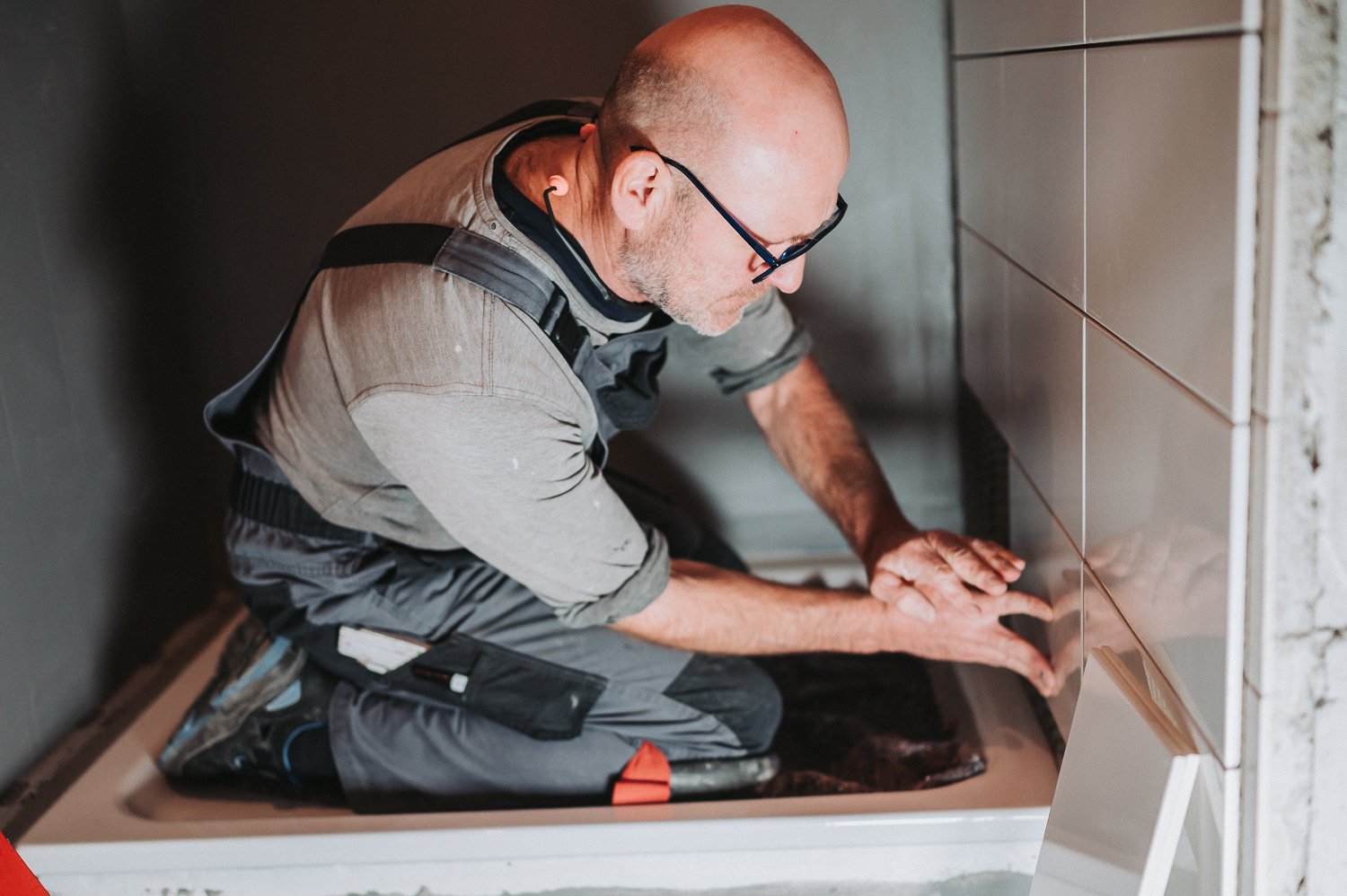 Ein Handwerker, vermutlich ein Installateur, installiert Fliesen in einer Küche oder einem Bad.