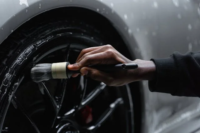 A person cleaning or polishing a car tire with a brush.