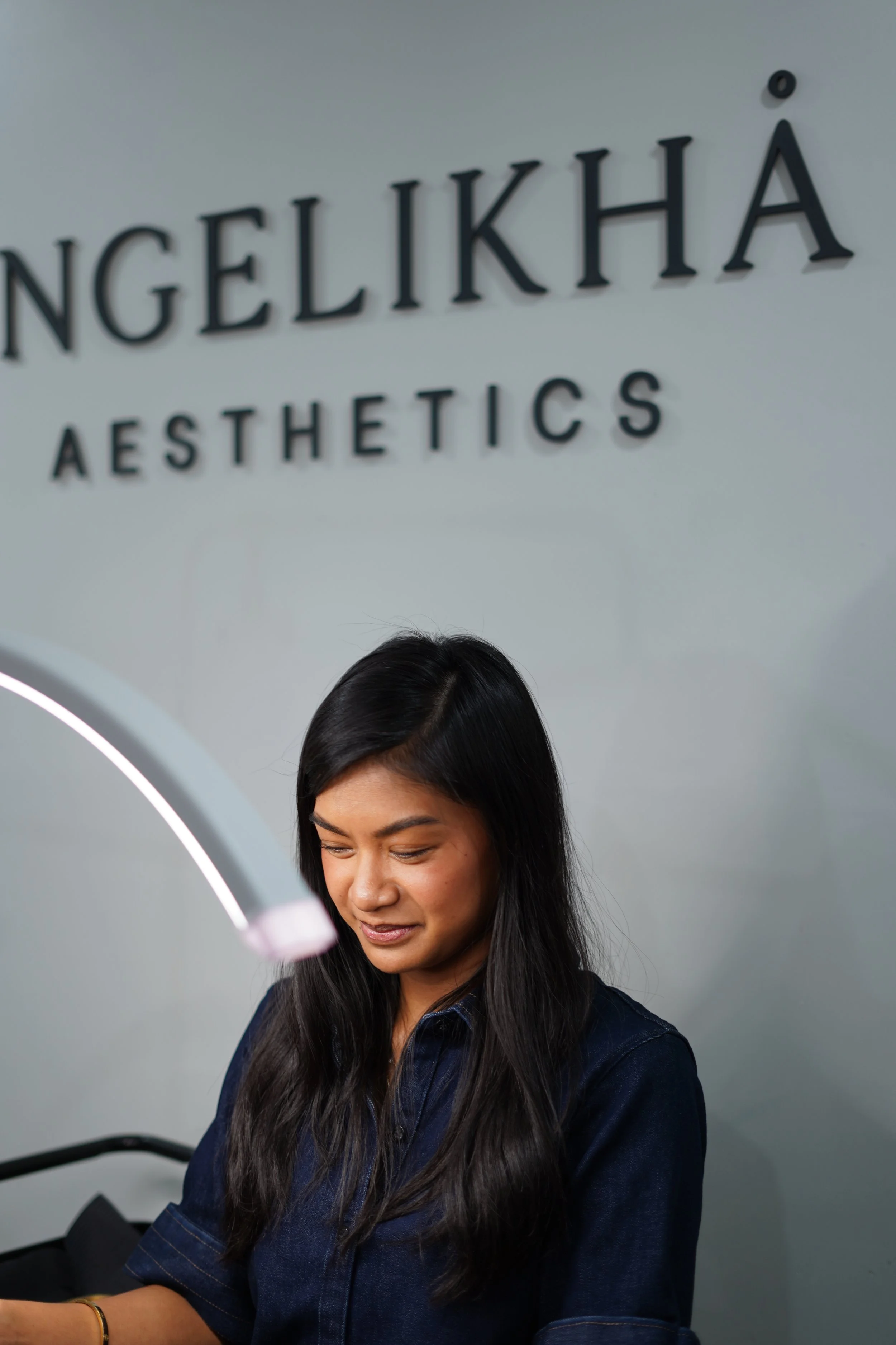 A woman with long dark hair getting a facial treatment at Angelikha Aesthetics clinic.