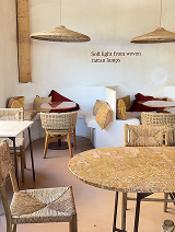 Cozy cafe seating with wicker chairs, a round table, and a white wall with a quote about salt and lemon.
