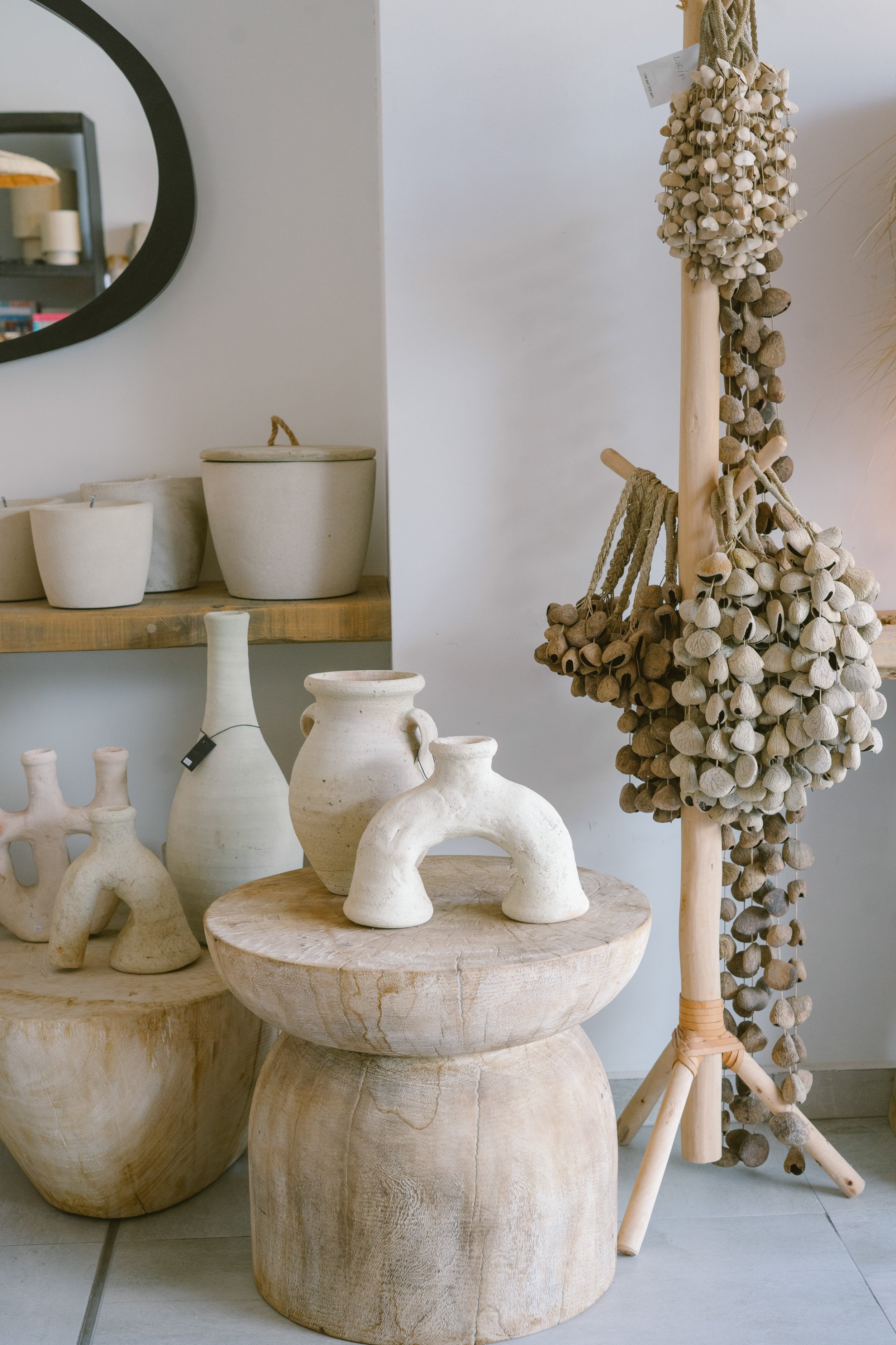 Display of rustic decorative pottery and dried plants in a neutral-toned home decor store.