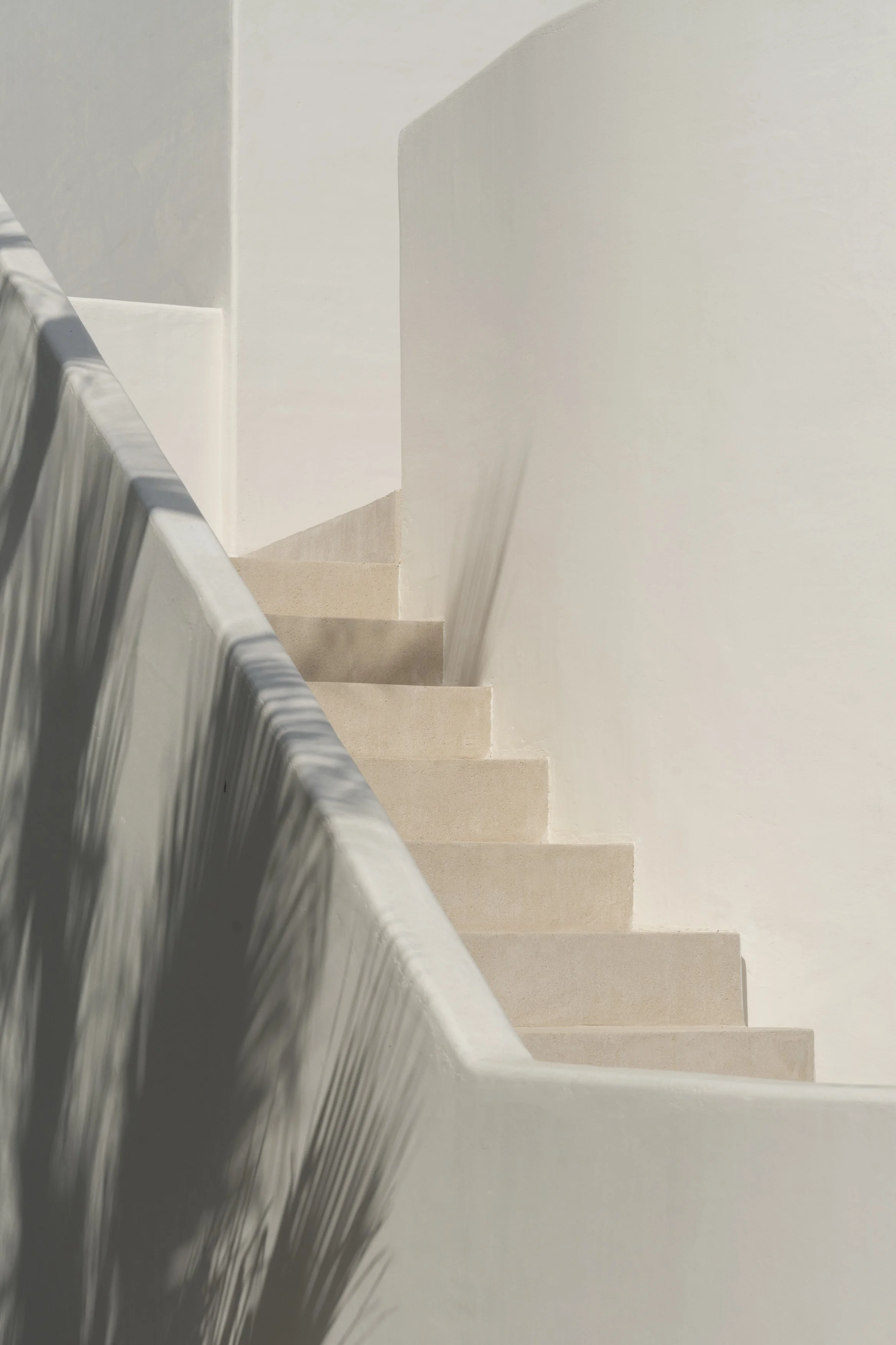 A stairway with beige steps and white walls, viewed from above.