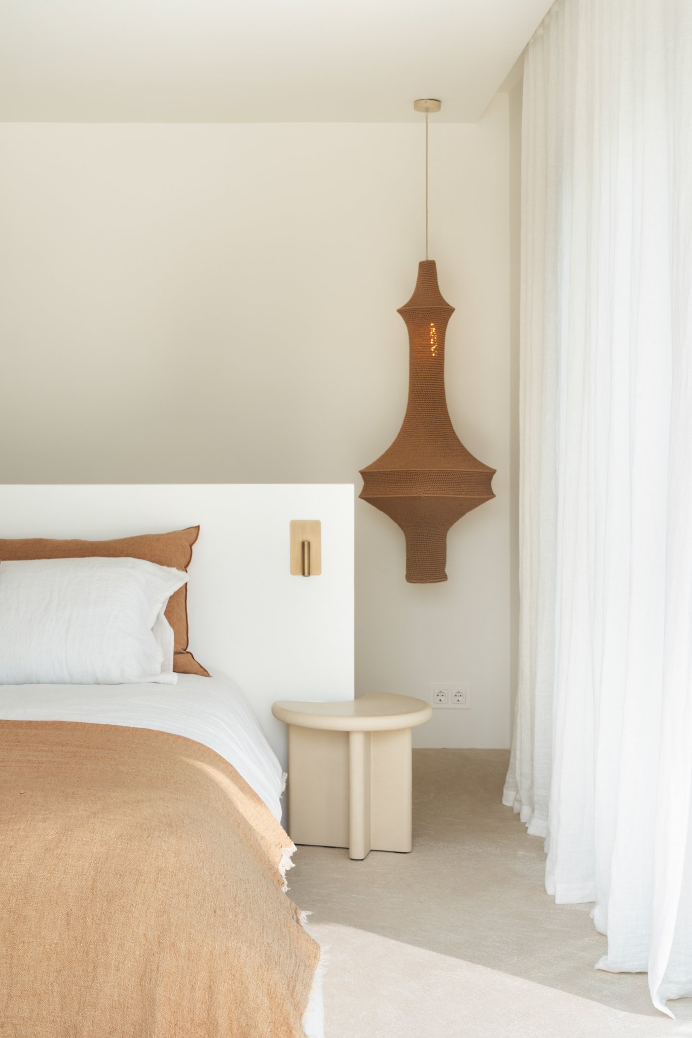 A bedroom furnished by A concept store Moraira at the costa blanca. Designed to be romantic, relaxing and good vibes to relax. 
Comfortable bed with mortex side table  and light terracotta colors and a matching knitted hanging lamp. 