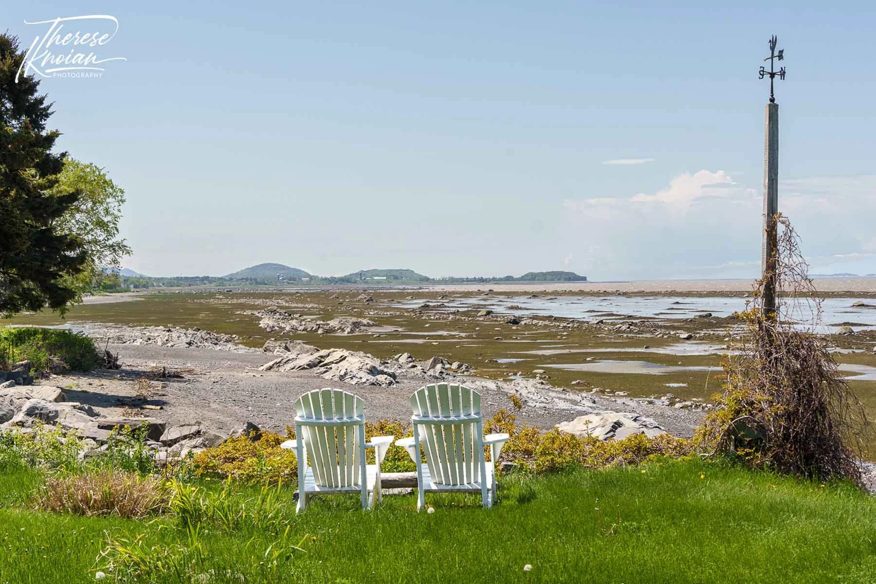 Two Adironack chairs on a rocky beach in Quebec Maritime